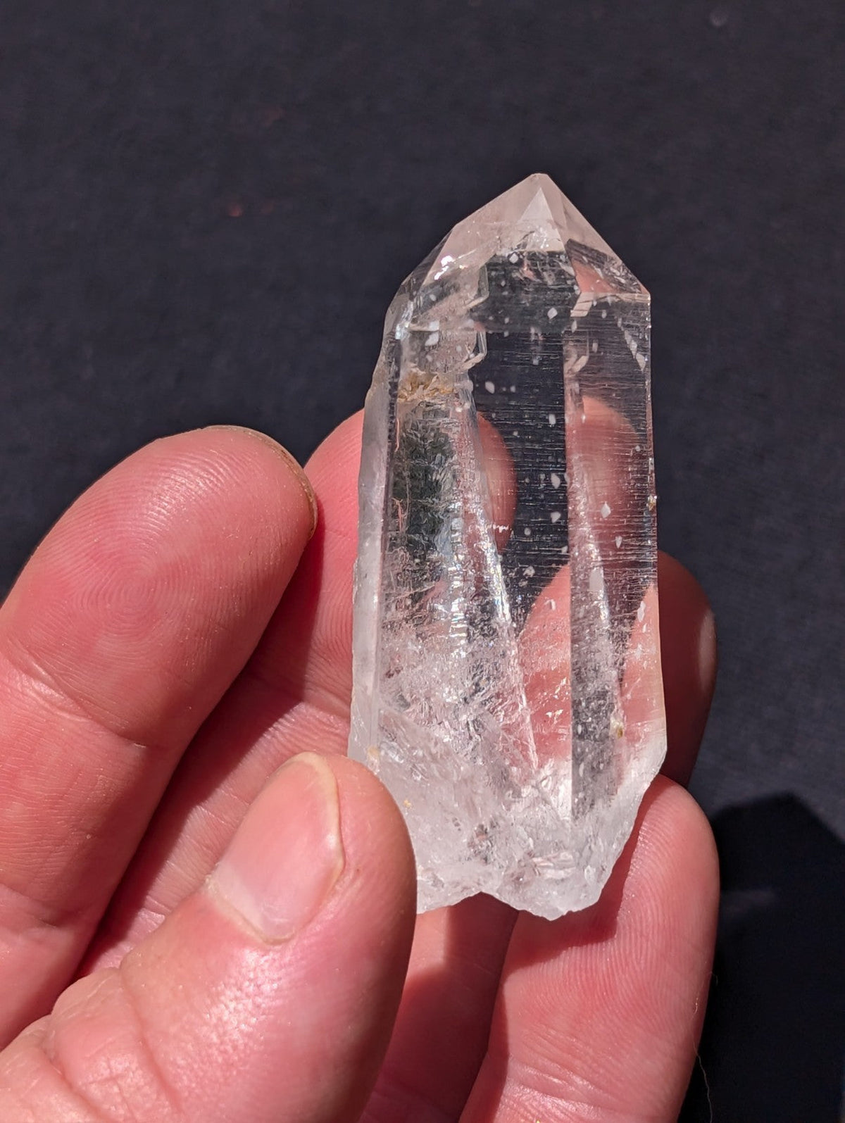 A clear, translucent quartz crystal with a pointed tip and natural facets.