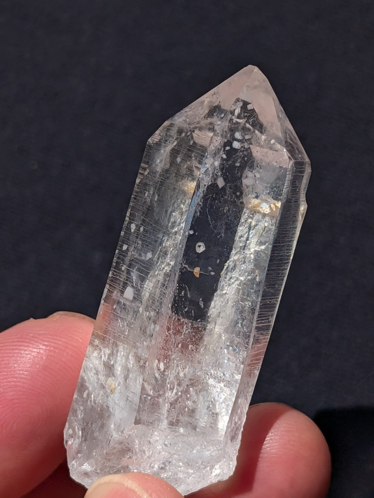 A clear, transparent quartz crystal with a pointed top and natural internal inclusions.