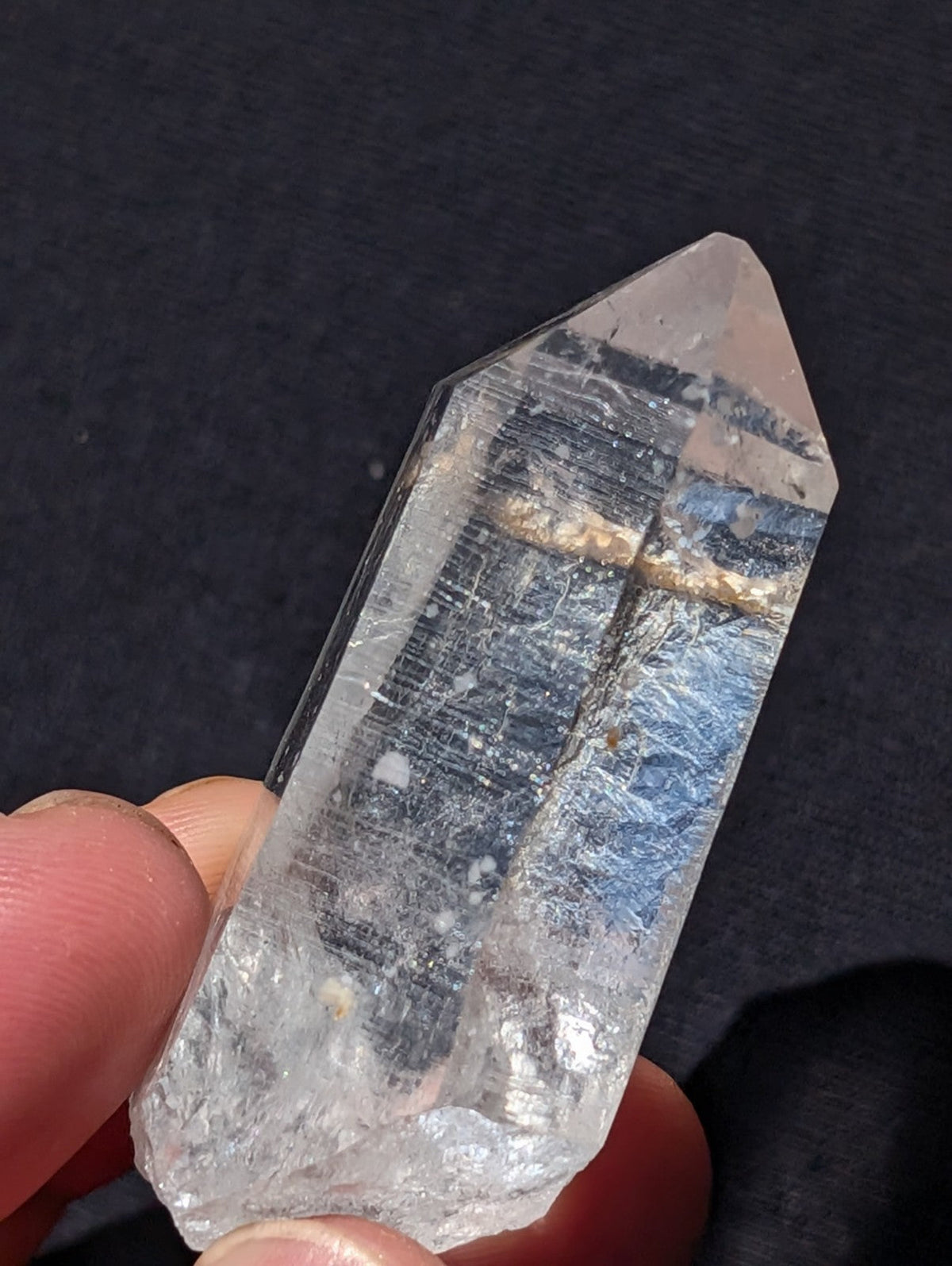 A clear, translucent quartz crystal with a pointed tip and visible internal striations.