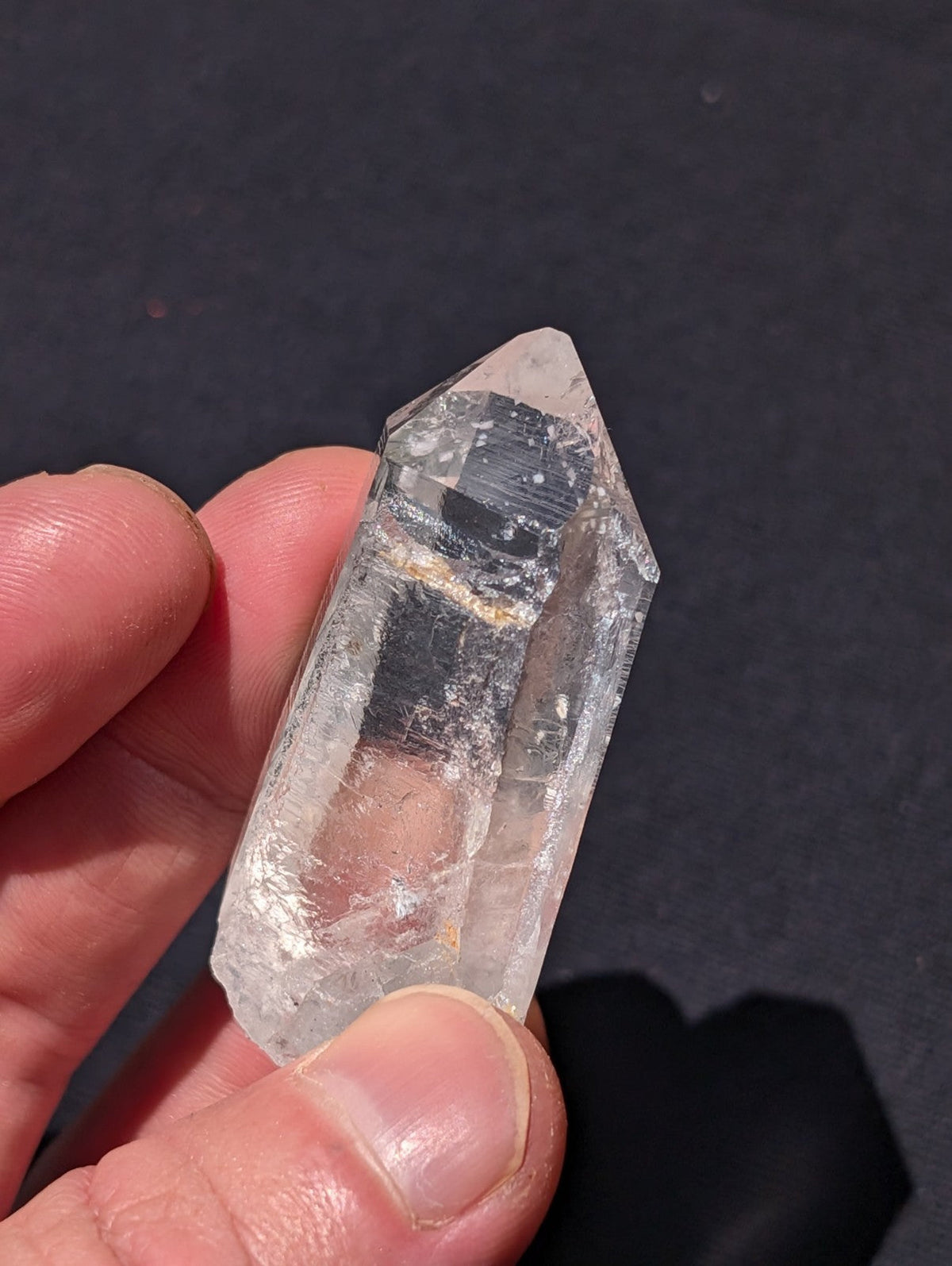 A clear, translucent quartz crystal with a pointed tip and natural inclusions.