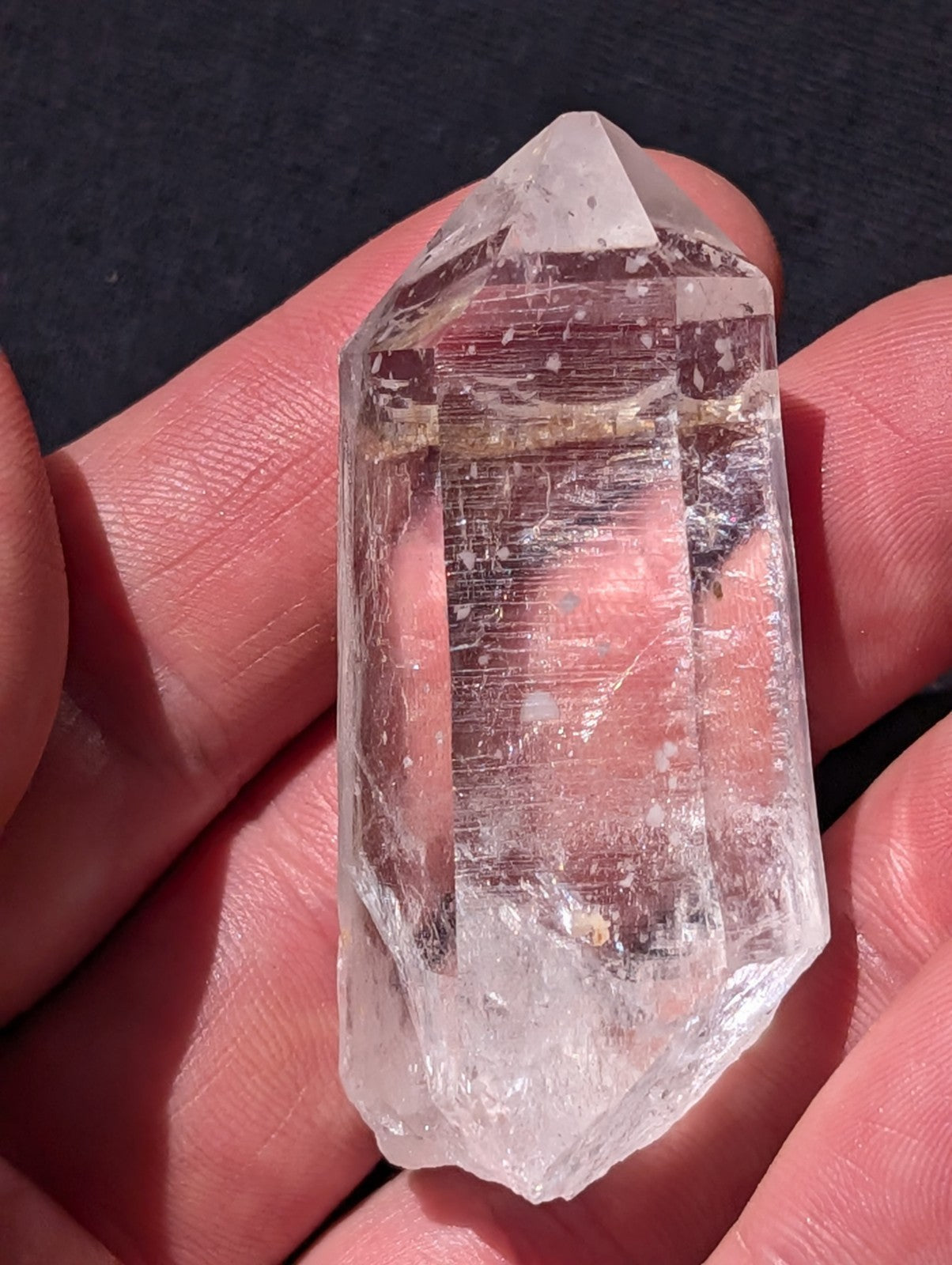 A clear, transparent quartz crystal with a pointed tip and natural inclusions.