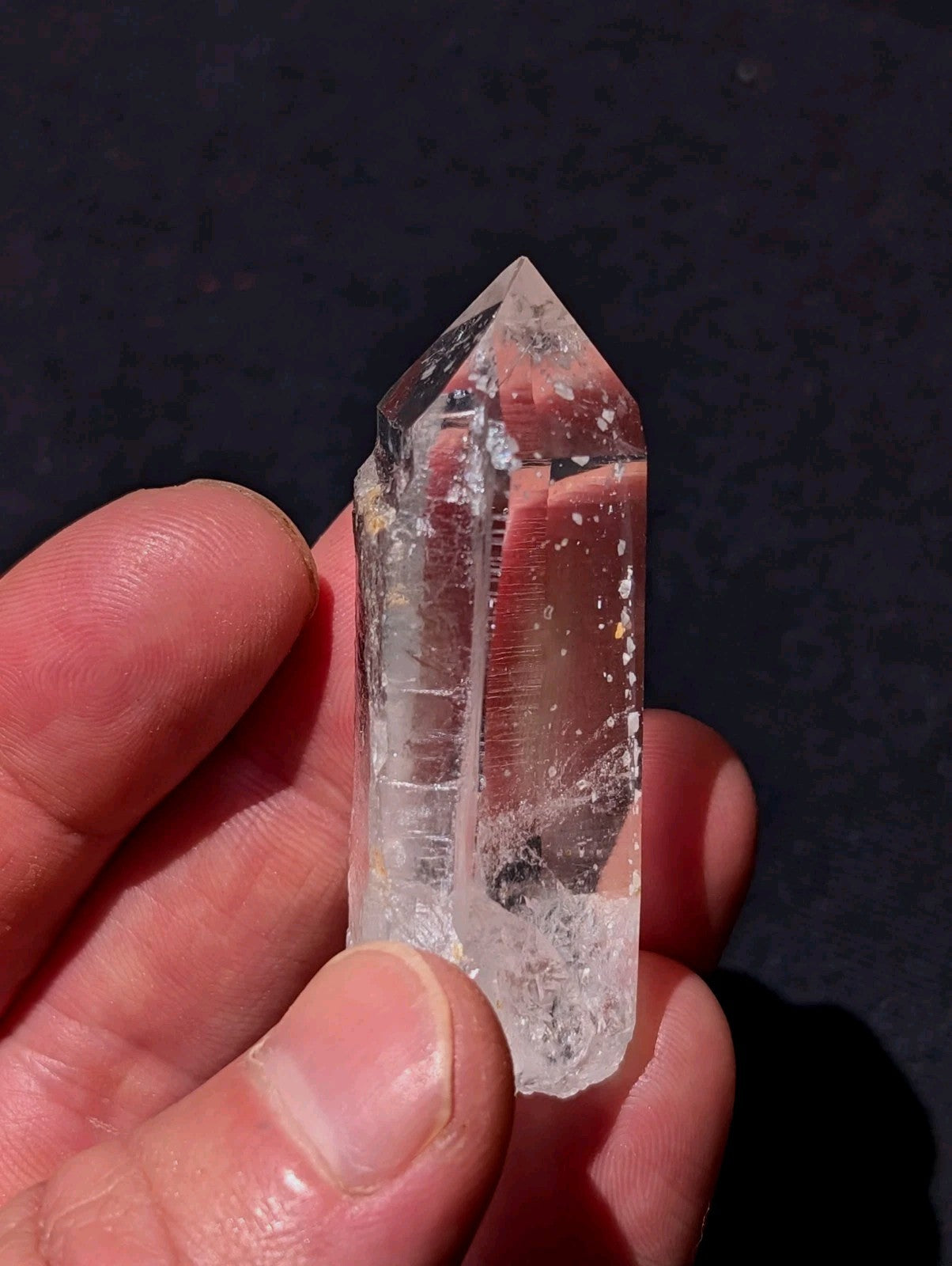 A clear, translucent quartz crystal with a pointed top and natural inclusions.
