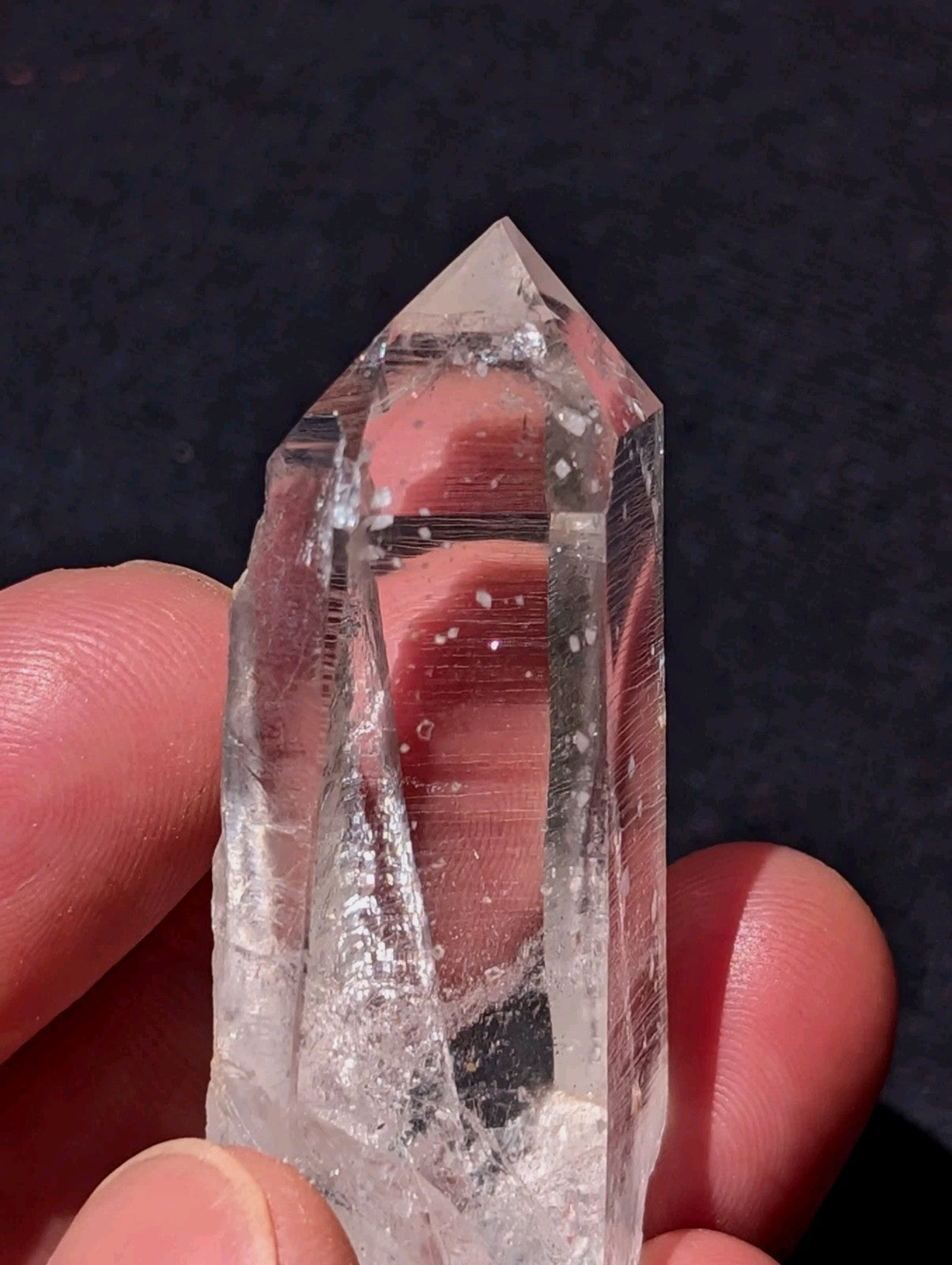 A clear, transparent quartz crystal with a pointed tip and visible internal inclusions.