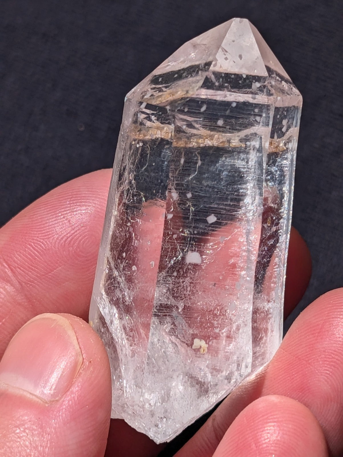 A clear, transparent quartz crystal with a pointed tip and natural inclusions.