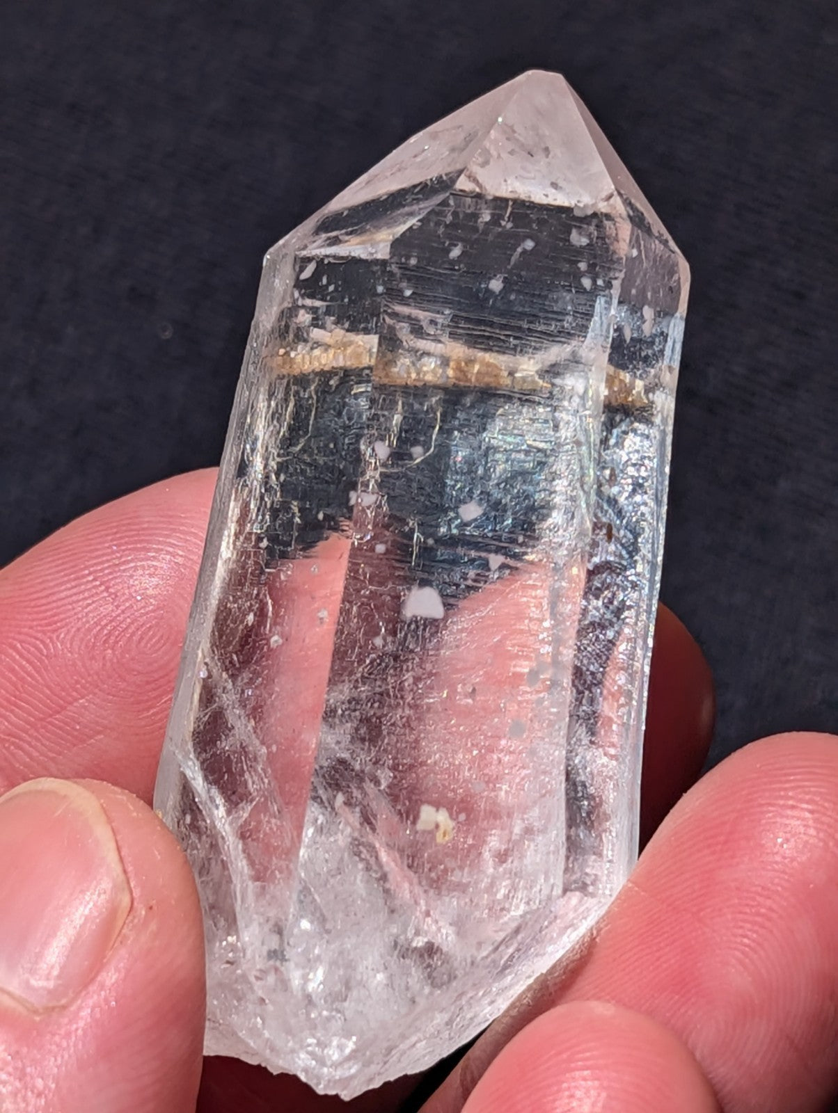 A clear, transparent quartz crystal with a pointed tip and natural internal inclusions.