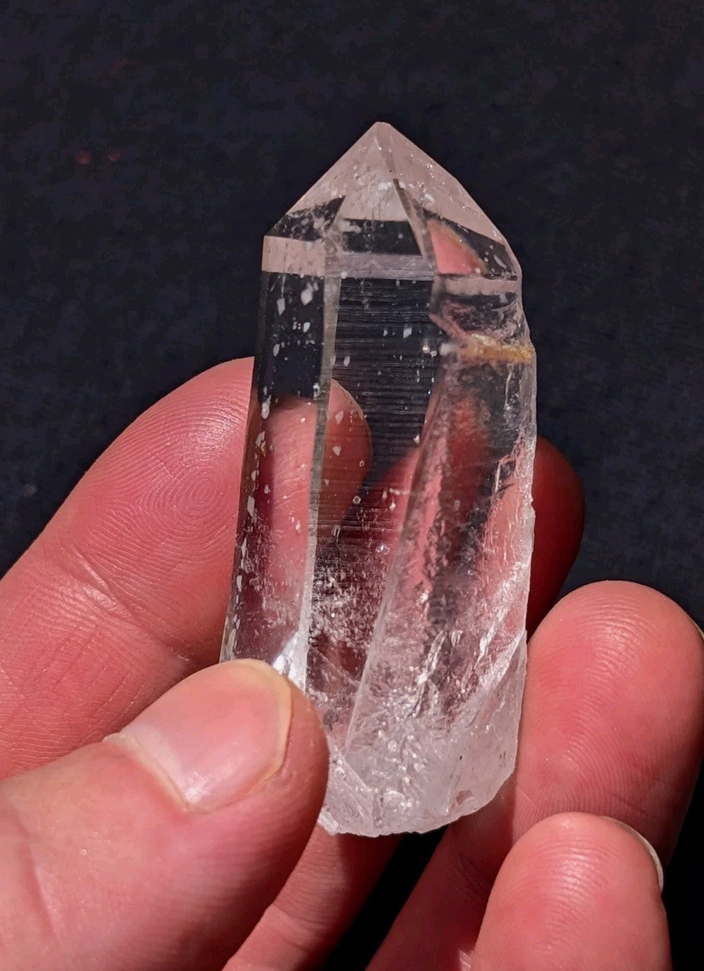 A clear, transparent quartz crystal with a pointed tip and natural facets.