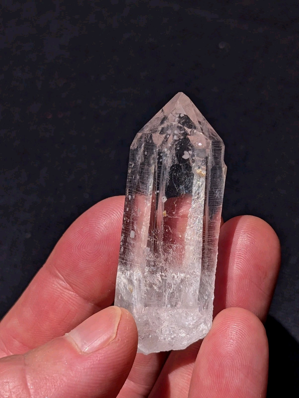 A clear, translucent quartz crystal with a pointed top and natural internal inclusions.