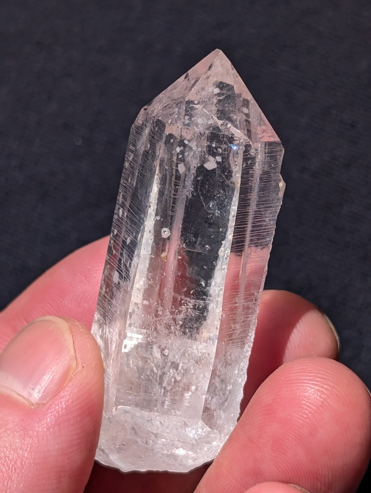 A clear, transparent quartz crystal with a pointed top and visible internal striations.