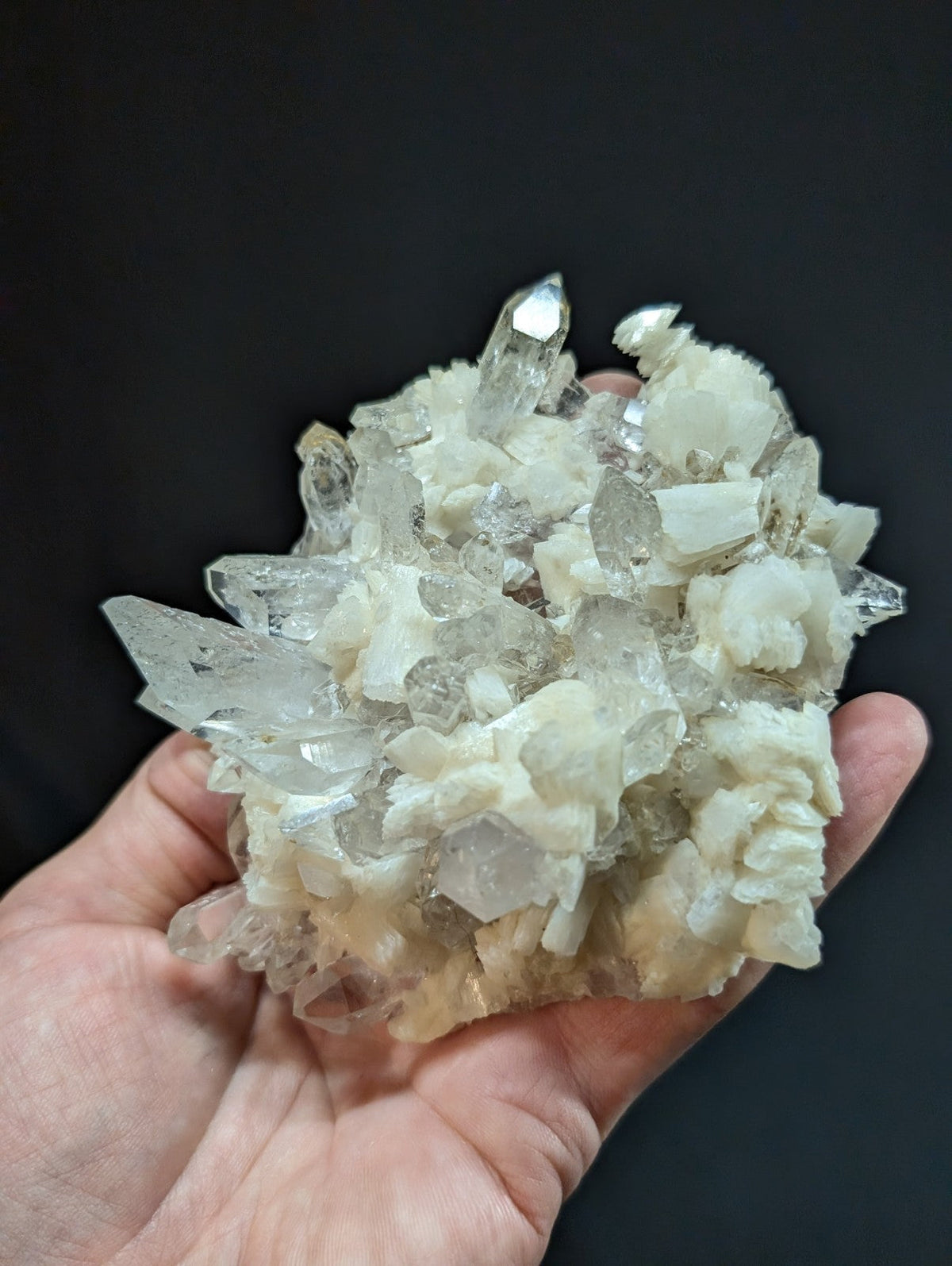 A cluster of translucent quartz crystals with sharp, pointed tips and a mix of clear and milky white hues.
