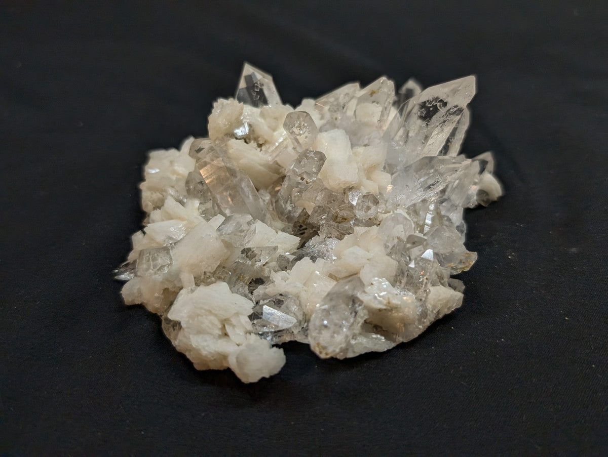 A cluster of translucent quartz crystals with sharp, faceted points and a mix of clear and milky white hues.