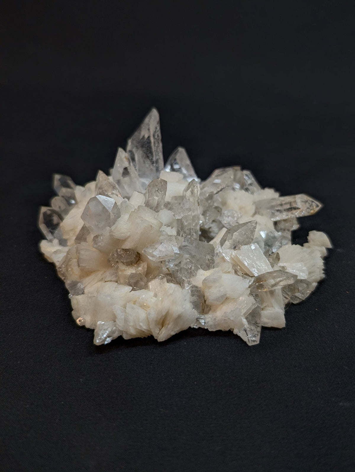 A cluster of clear, faceted quartz crystals with a white matrix base.