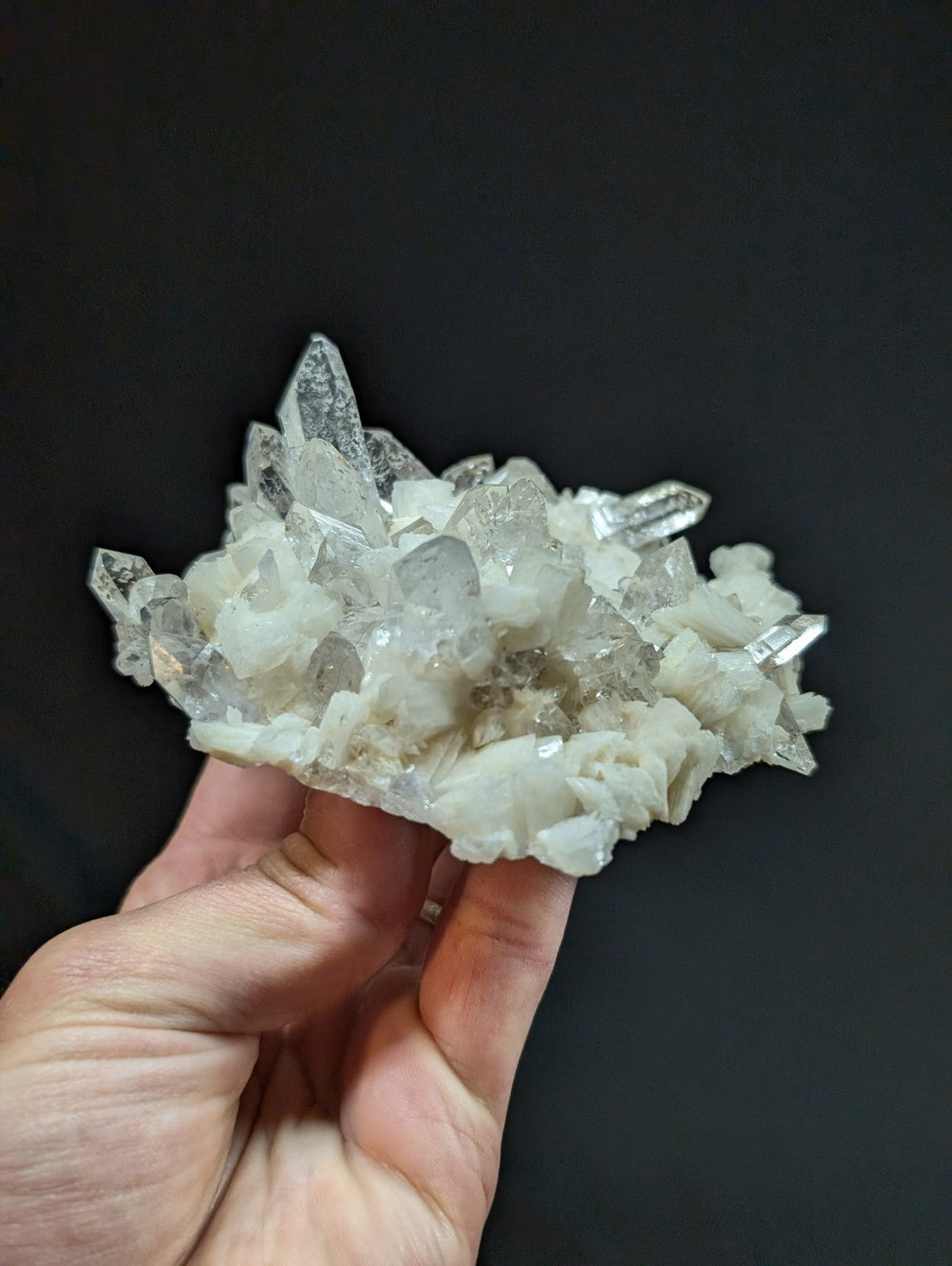 A translucent white quartz crystal cluster with sharp, pointed facets and a rough-textured base.