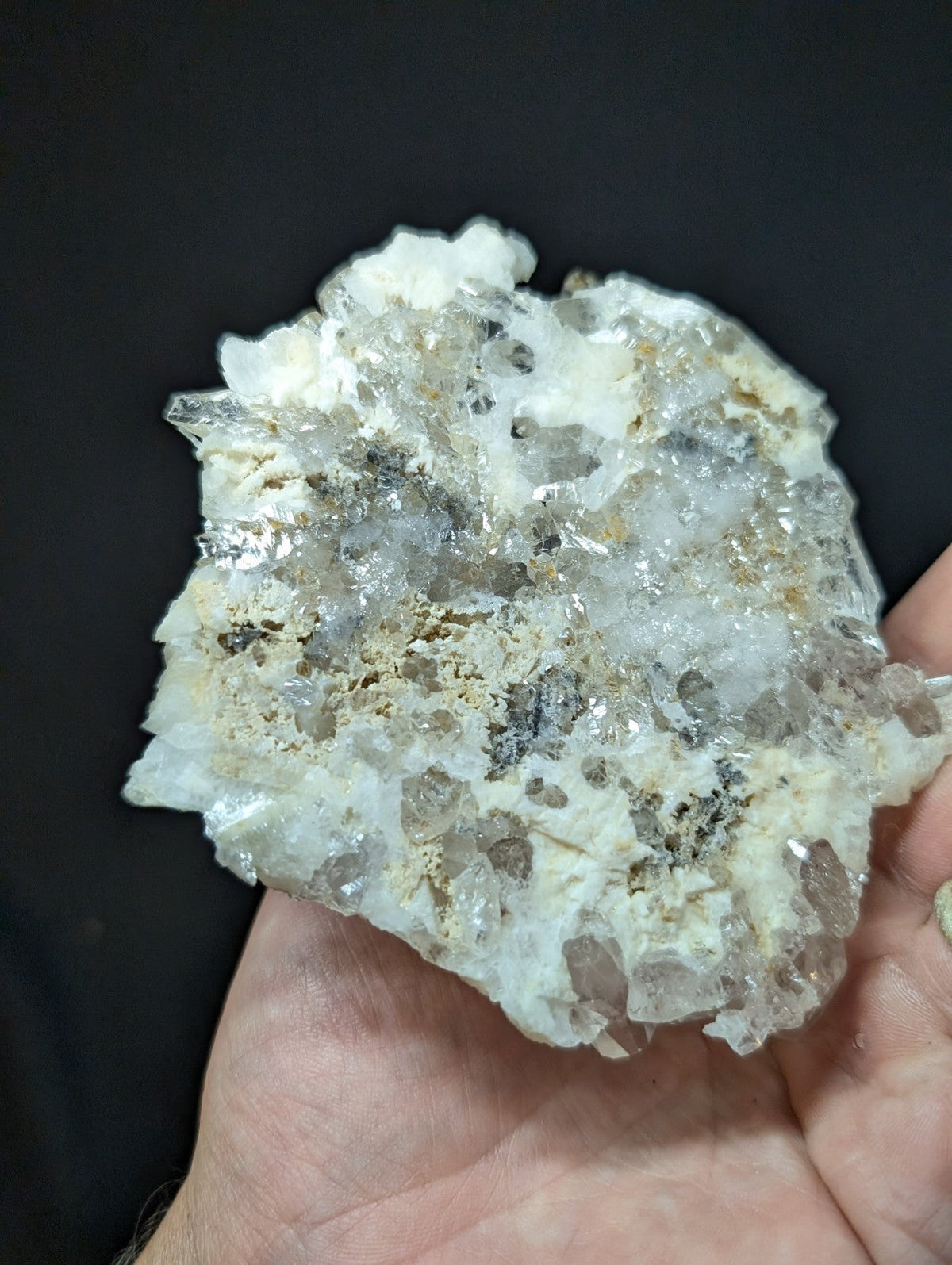 A translucent, crystalline mineral specimen with a mix of clear and milky white quartz crystals intergrown with dark gray inclusions.