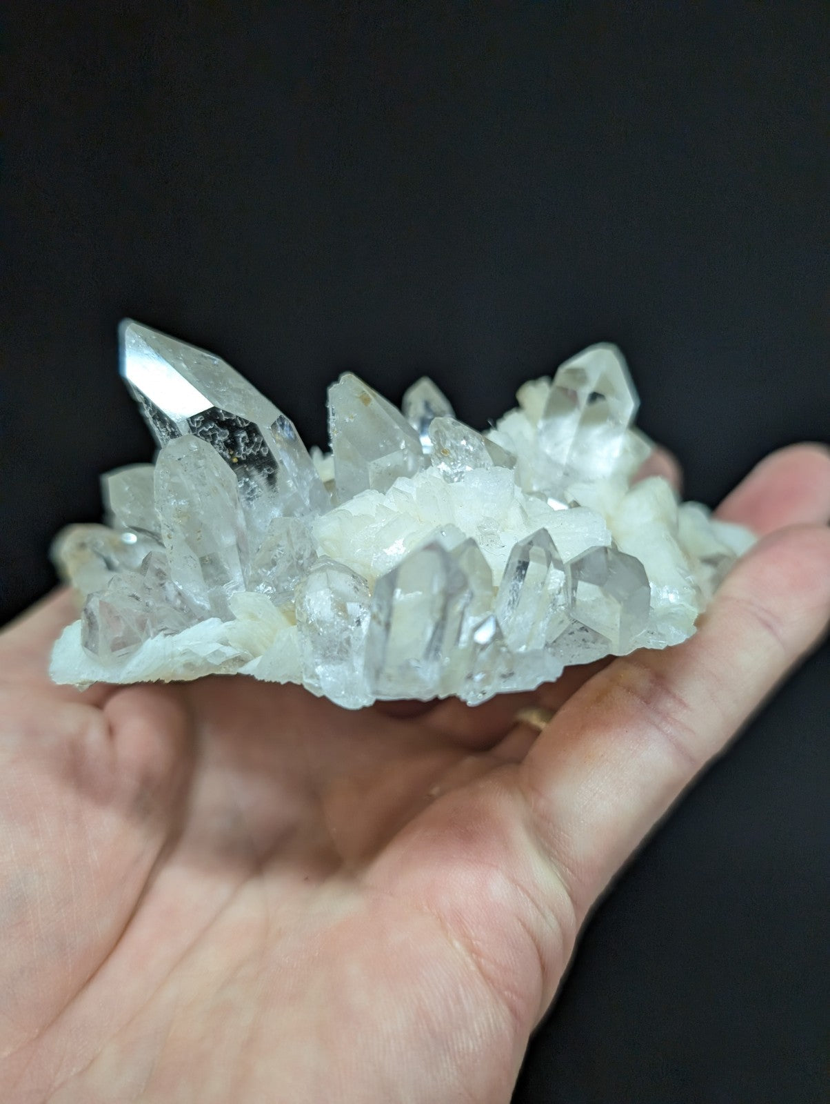 A translucent, clear quartz crystal cluster with sharp, faceted points and a slightly frosted base.