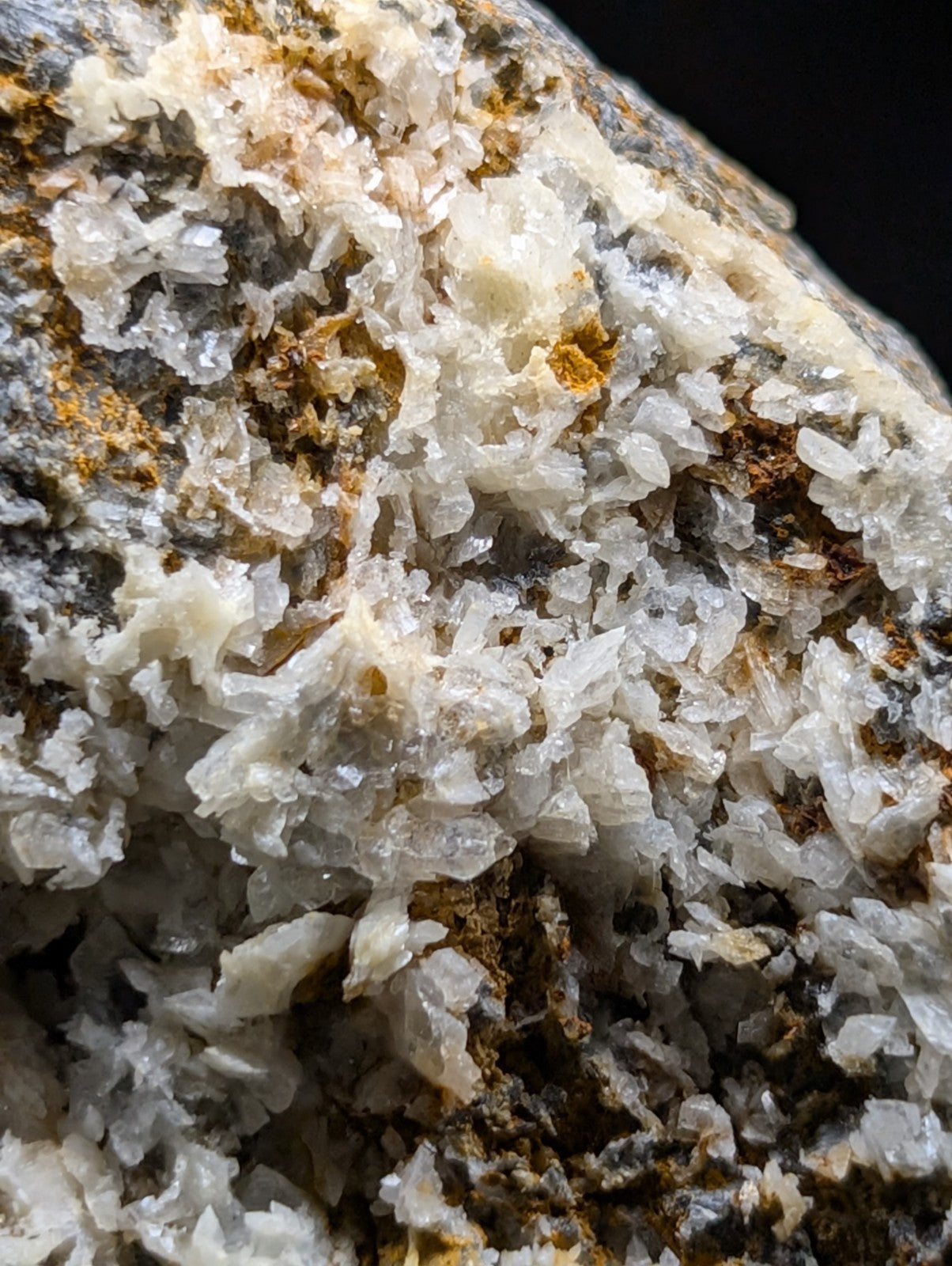 A cluster of translucent, crystalline minerals with a mix of white and pale yellow hues embedded in darker rock.