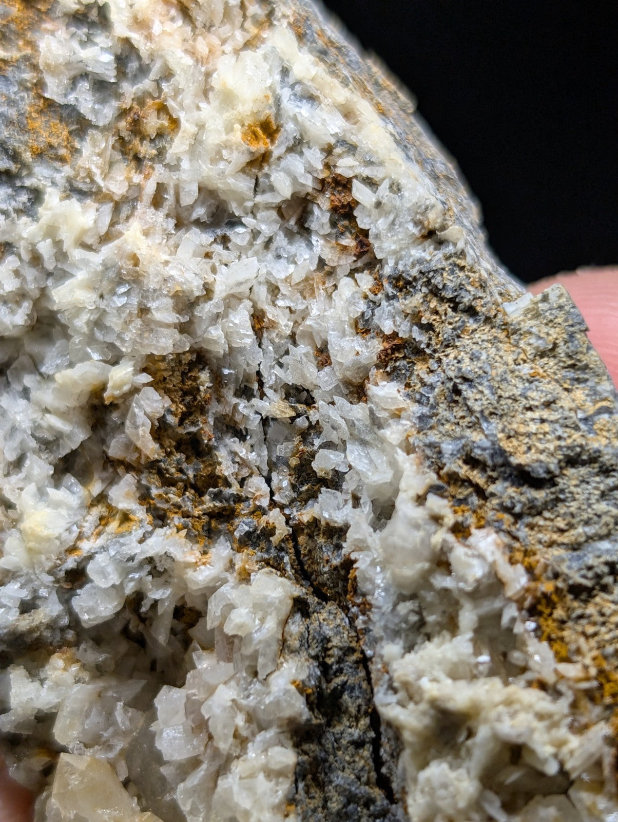 A rugged, naturally occurring mineral specimen featuring translucent white crystals intermingled with earthy gray and orange-brown matrix material.