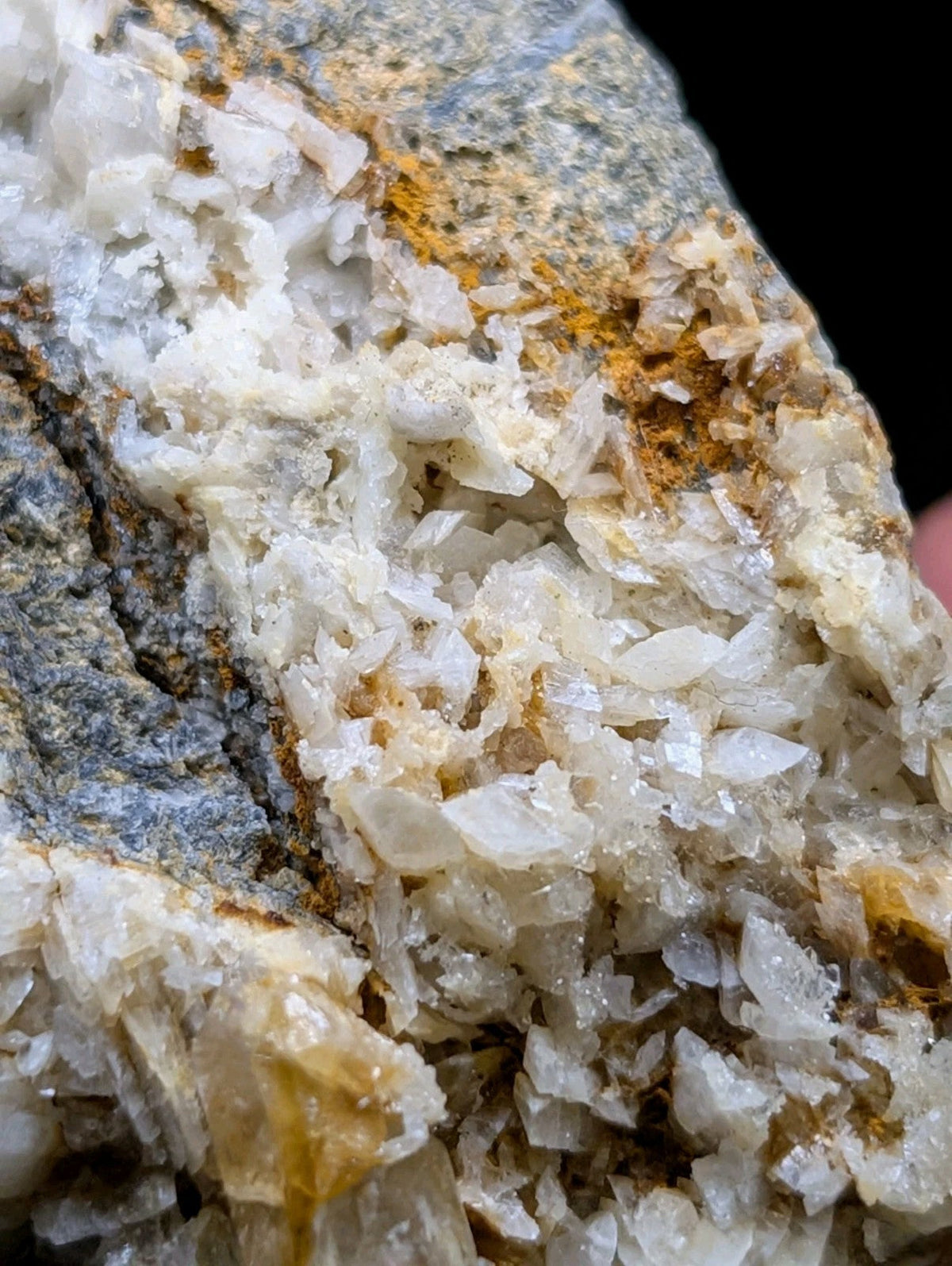 A translucent white crystalline mineral formation with golden-yellow streaks, embedded in a gray rock matrix.