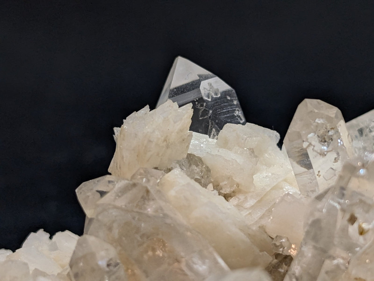 A cluster of translucent, pale quartz crystals with sharp geometric facets and subtle internal inclusions.