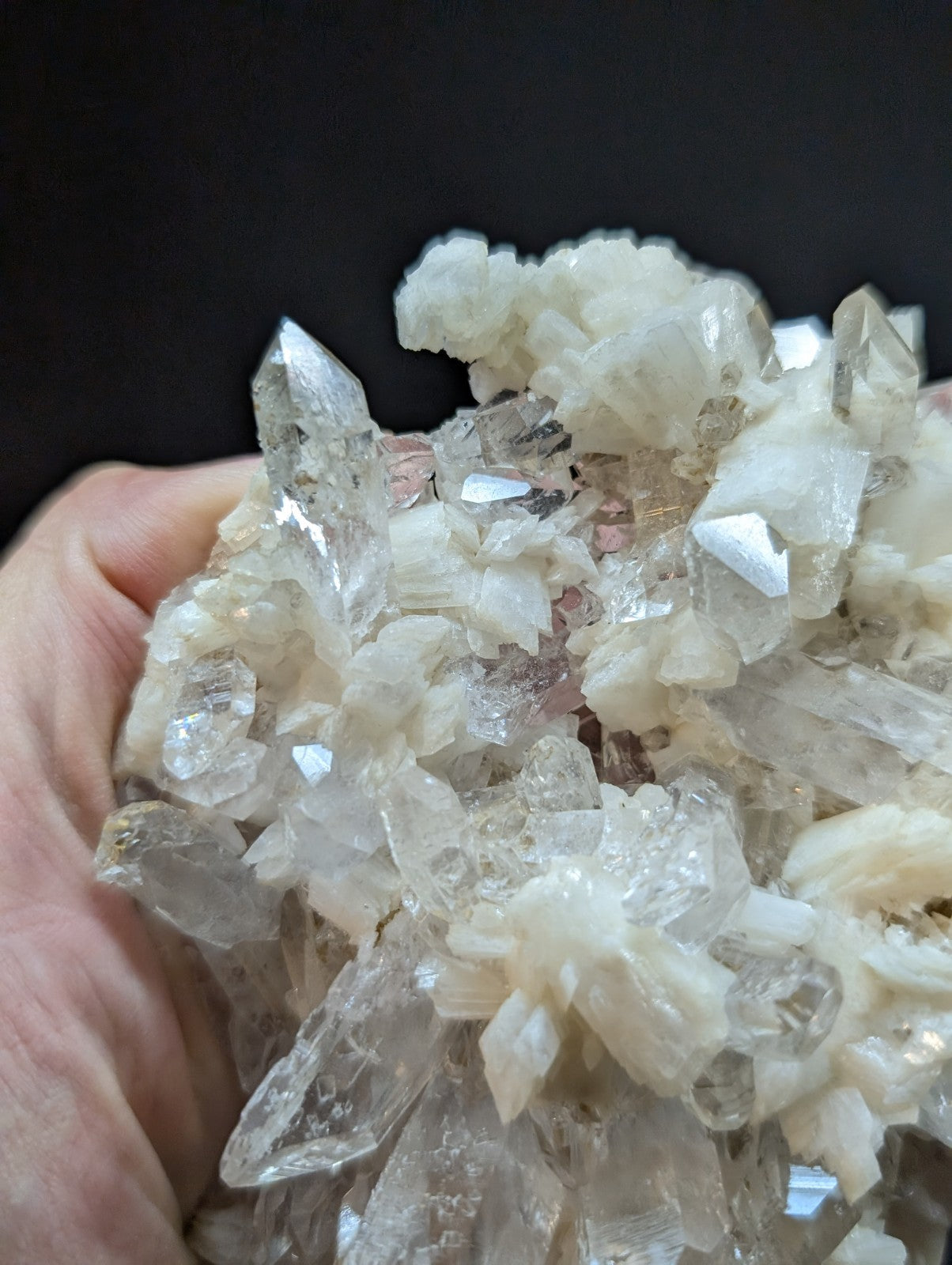 A cluster of translucent, clear quartz crystals with some exhibiting subtle pinkish hues and sharp, faceted points.