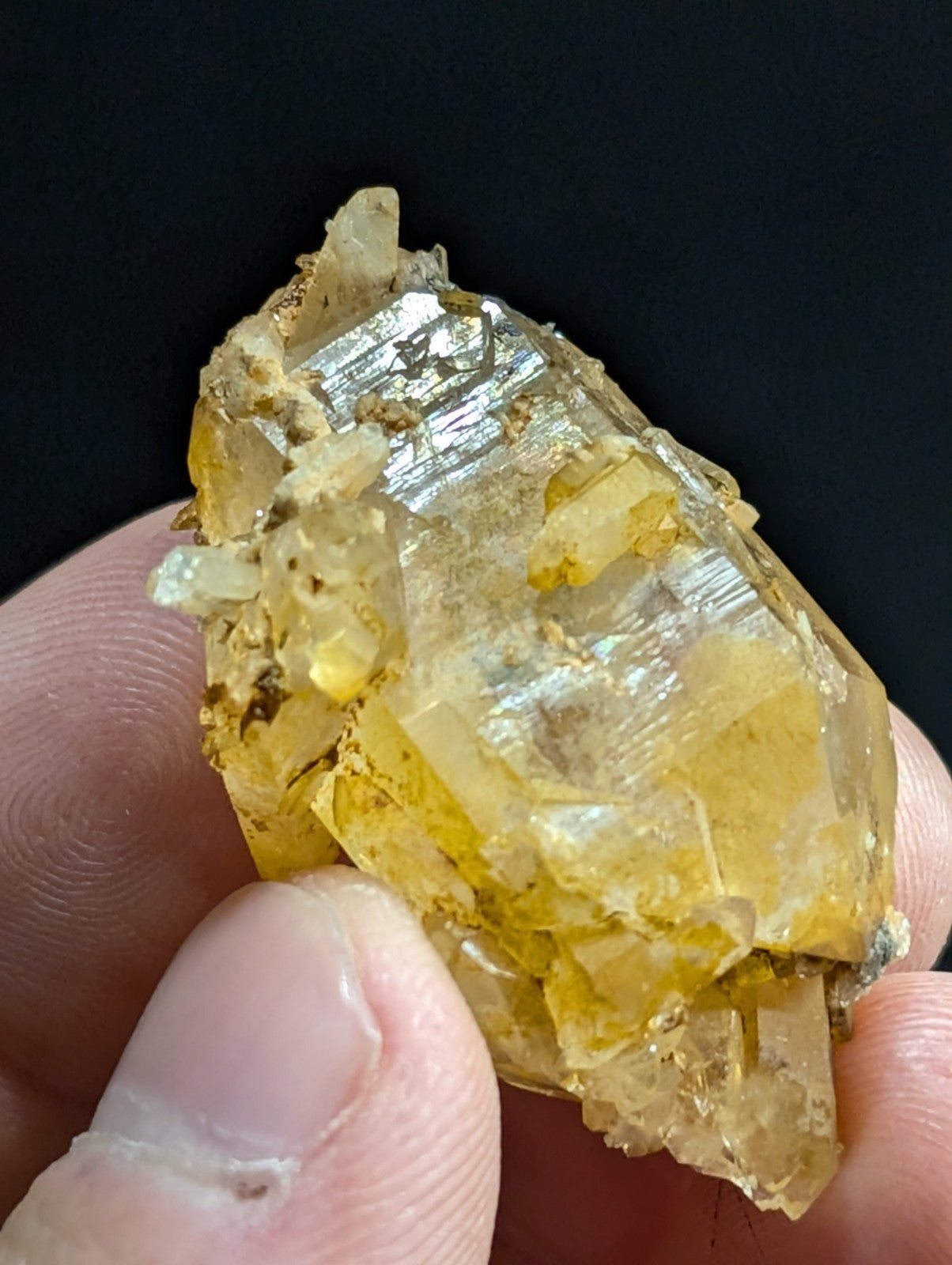 A translucent yellow crystal with a faceted, glassy surface and embedded metallic inclusions.
