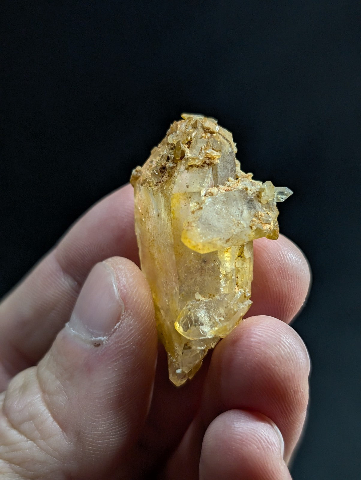 A translucent yellow crystal with a rough, earthy base and clear facets.