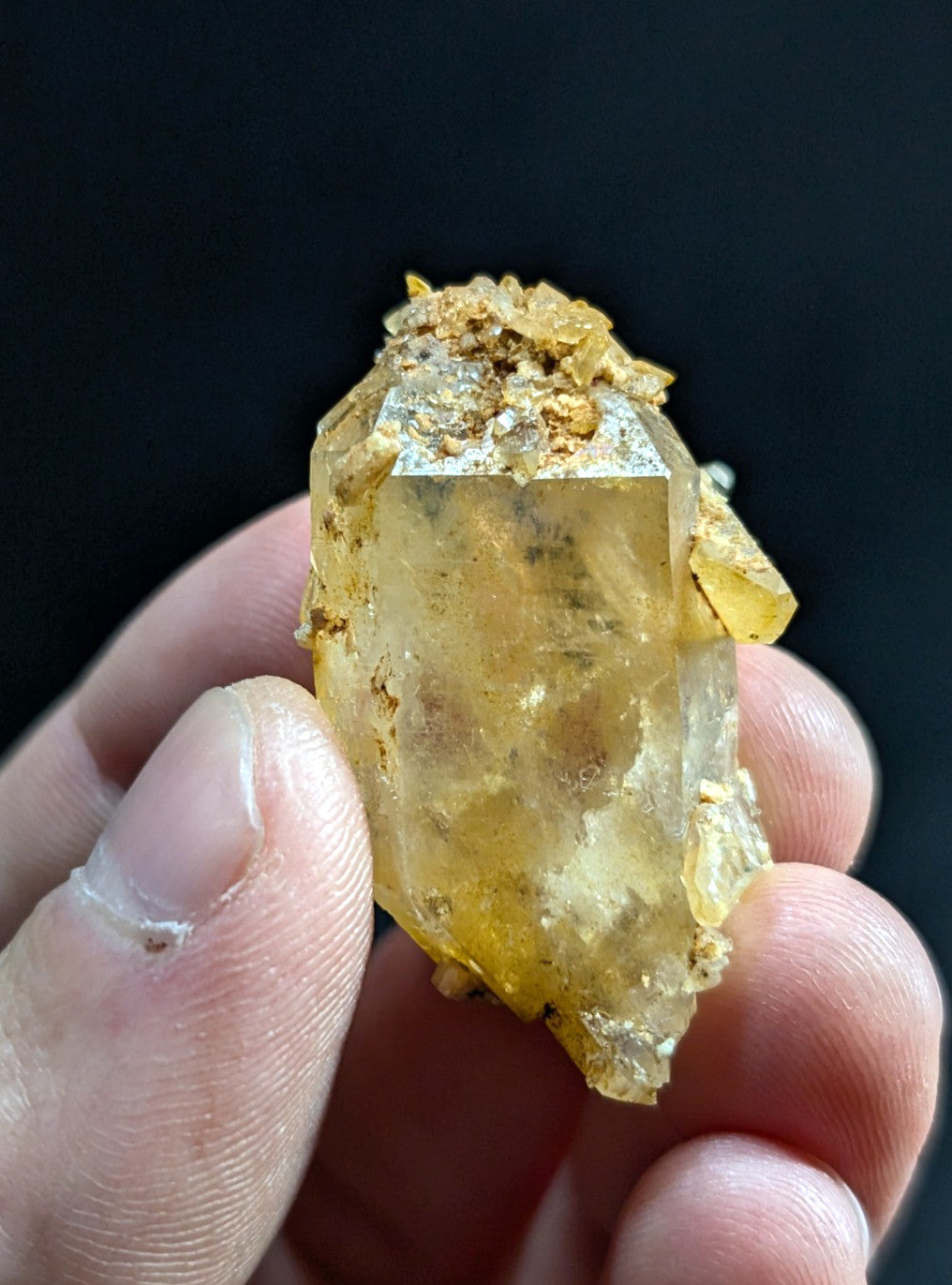 A translucent yellowish quartz crystal with a rough, earthy matrix and visible internal inclusions.