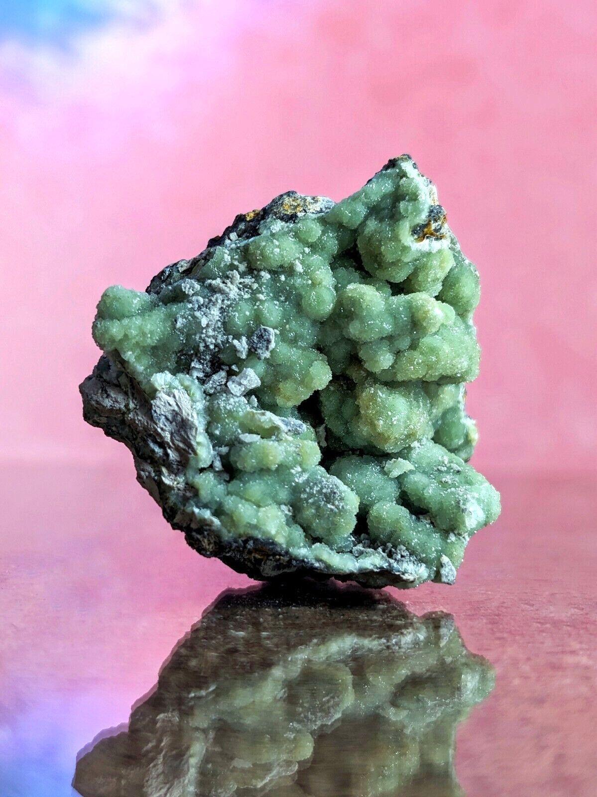 A vibrant green, textured mineral specimen with a rough, clustered surface and dark base.