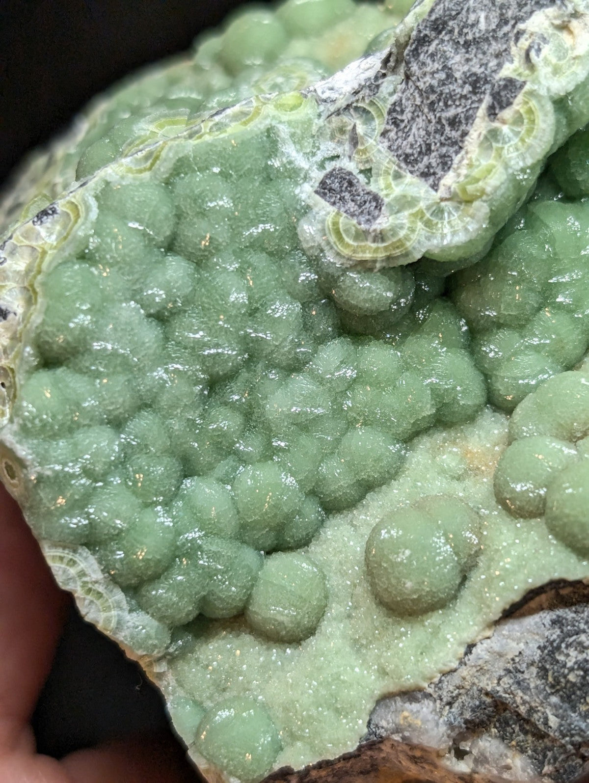 A vibrant green, bumpy mineral specimen with a glossy surface and intricate crystalline formations.
