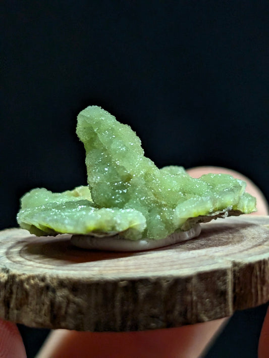 A translucent green crystal formation with a rough, jagged surface and sparkling facets.