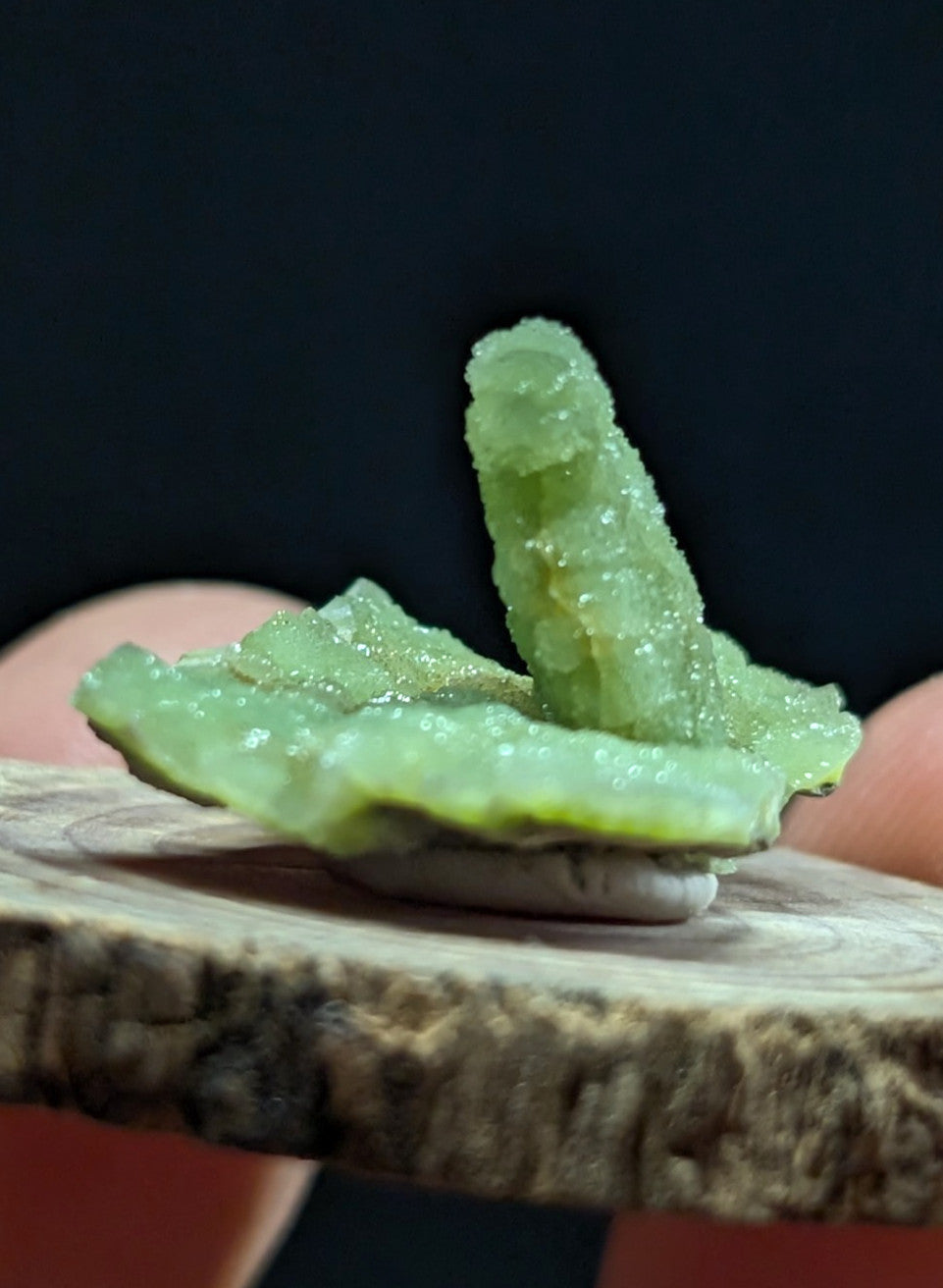 A translucent light green crystal formation with a rough, jagged surface and visible internal crystalline structure.