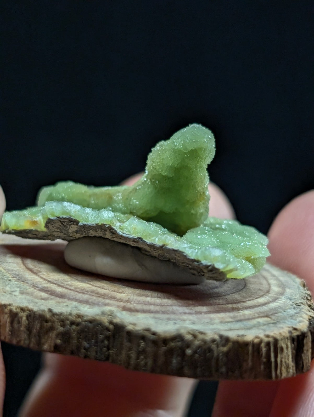 A translucent green crystal formation with a rough, crystalline texture and subtle yellowish inclusions.