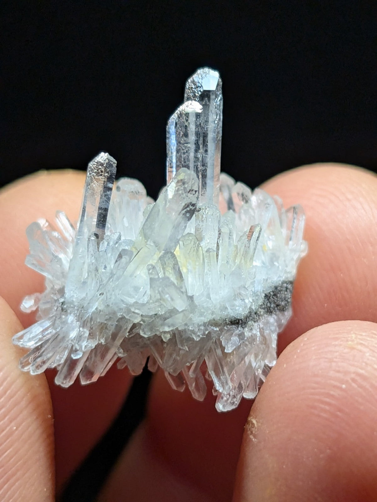 A translucent, pale blue crystal cluster with sharp, pointed facets and a delicate, branching structure.