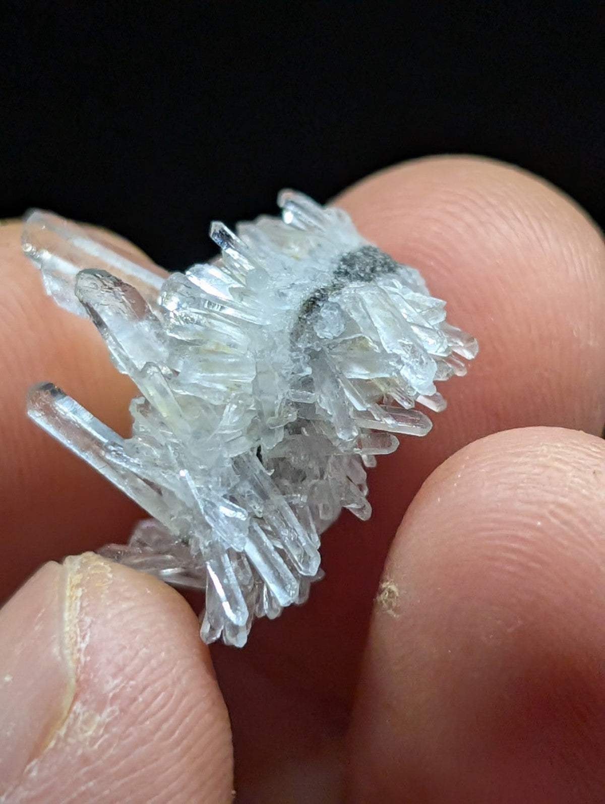 A cluster of clear, translucent quartz crystals with sharp, pointed tips and a natural, rough texture.