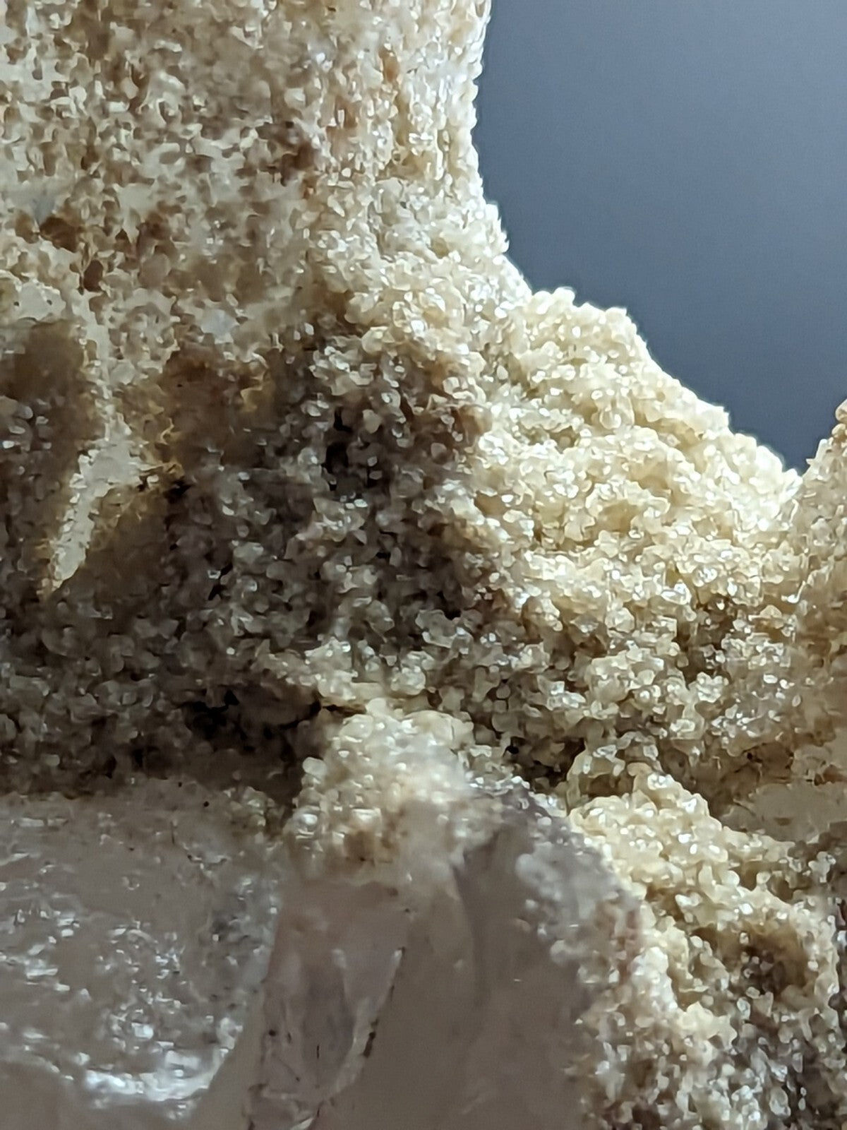 A creamy white, crystalline mineral formation with a textured, granular surface and subtle golden-brown accents.