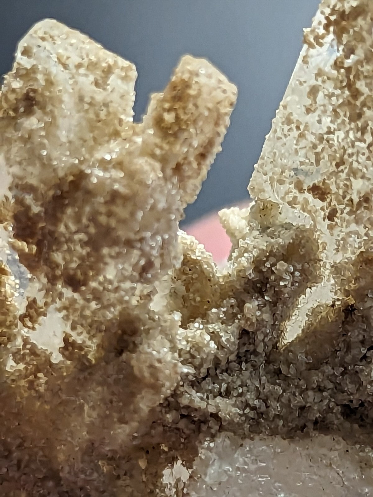 A translucent, crystalline mineral specimen with a rough, textured surface and golden-brown speckles.