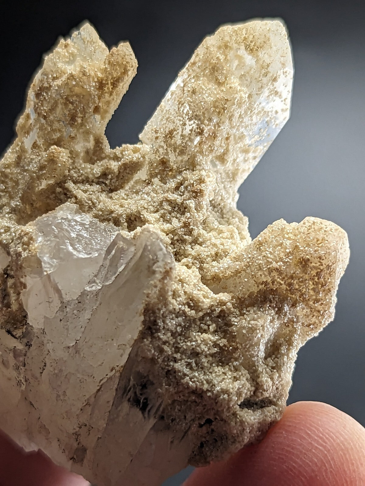 A translucent quartz crystal cluster with clear, pointed facets and a beige matrix.