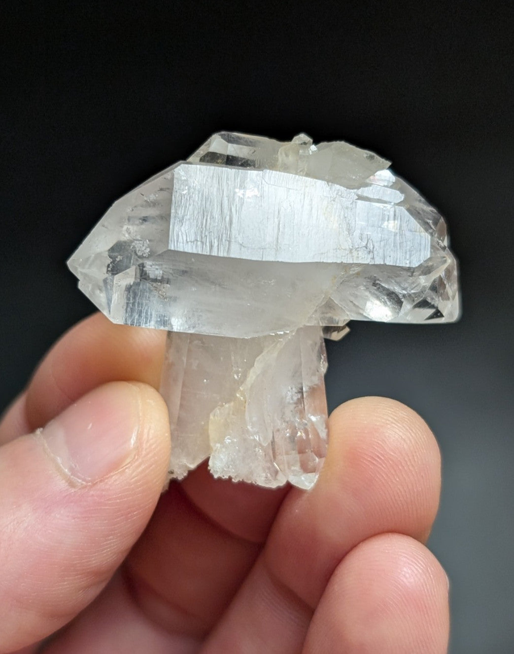 A clear, translucent quartz crystal formation shaped like a mushroom with faceted surfaces and visible internal striations.