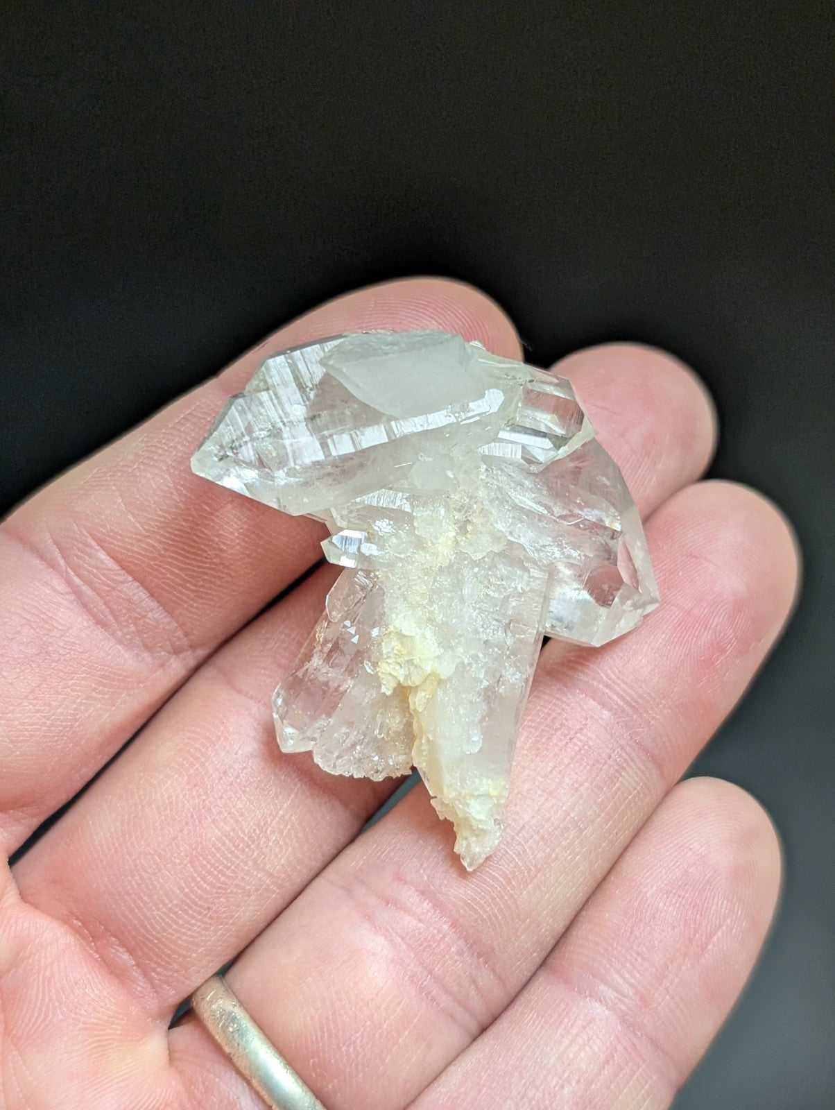 A translucent, pale greenish-white quartz crystal cluster with visible striations and a rough, natural formation.