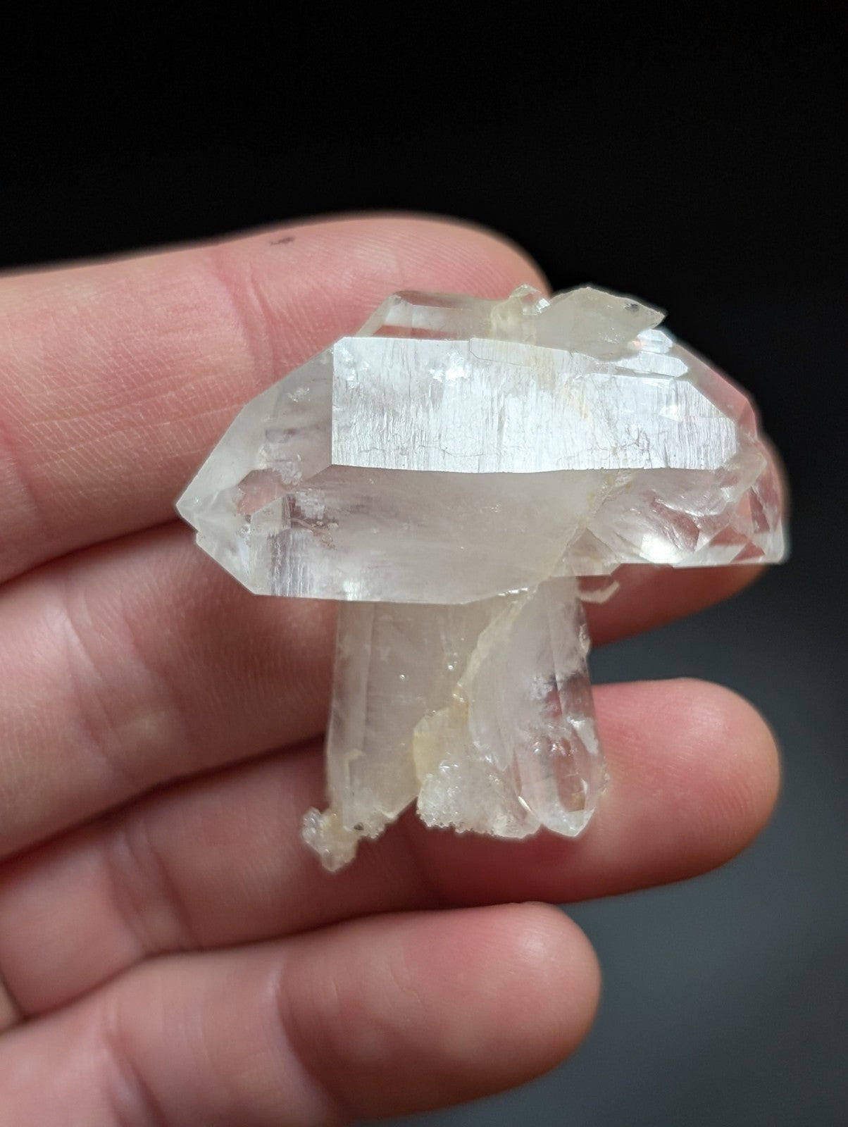 A translucent, clear quartz crystal formation with a distinct mushroom-like shape and visible internal striations.