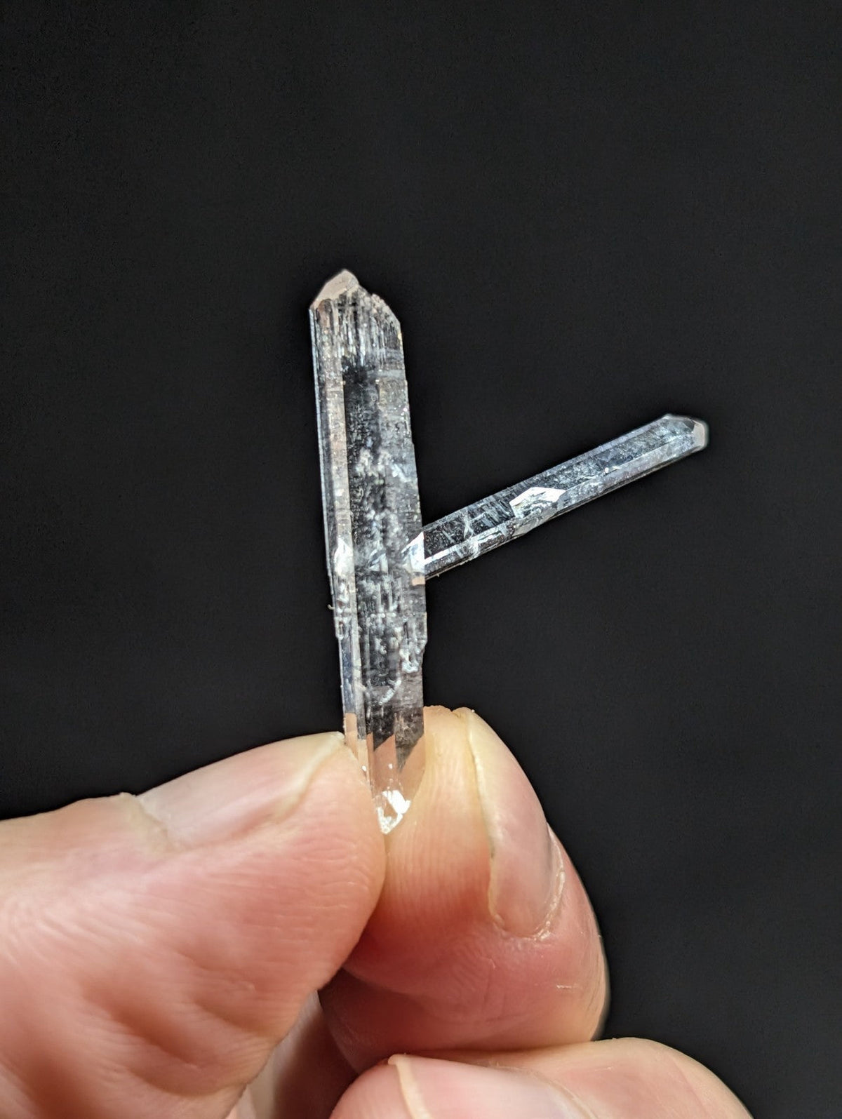 A clear, translucent quartz crystal formation with a pointed tip and visible internal inclusions.