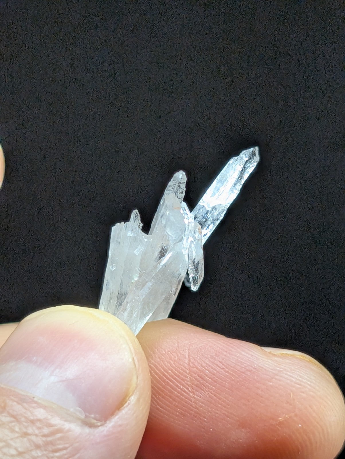 A translucent, clear quartz crystal cluster with sharp, pointed facets and a natural, jagged growth pattern.