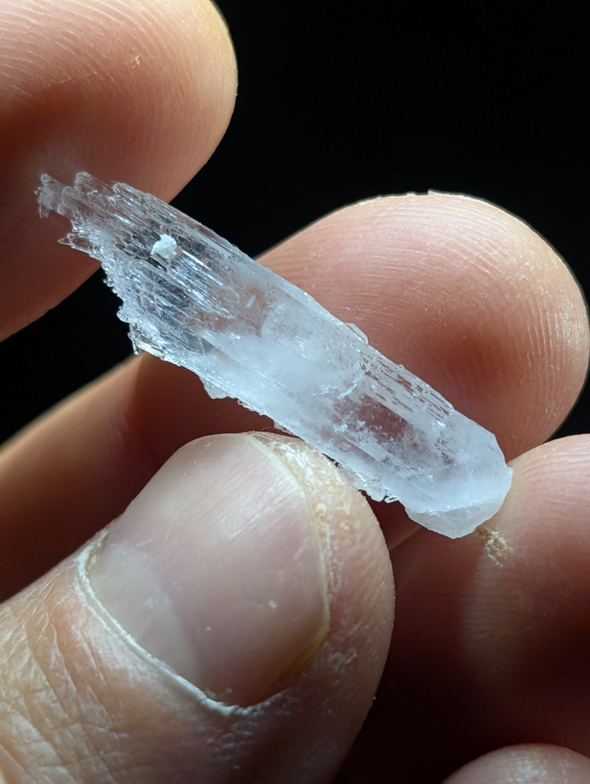 A translucent, pale blue crystal with a jagged, natural edge and visible internal striations.