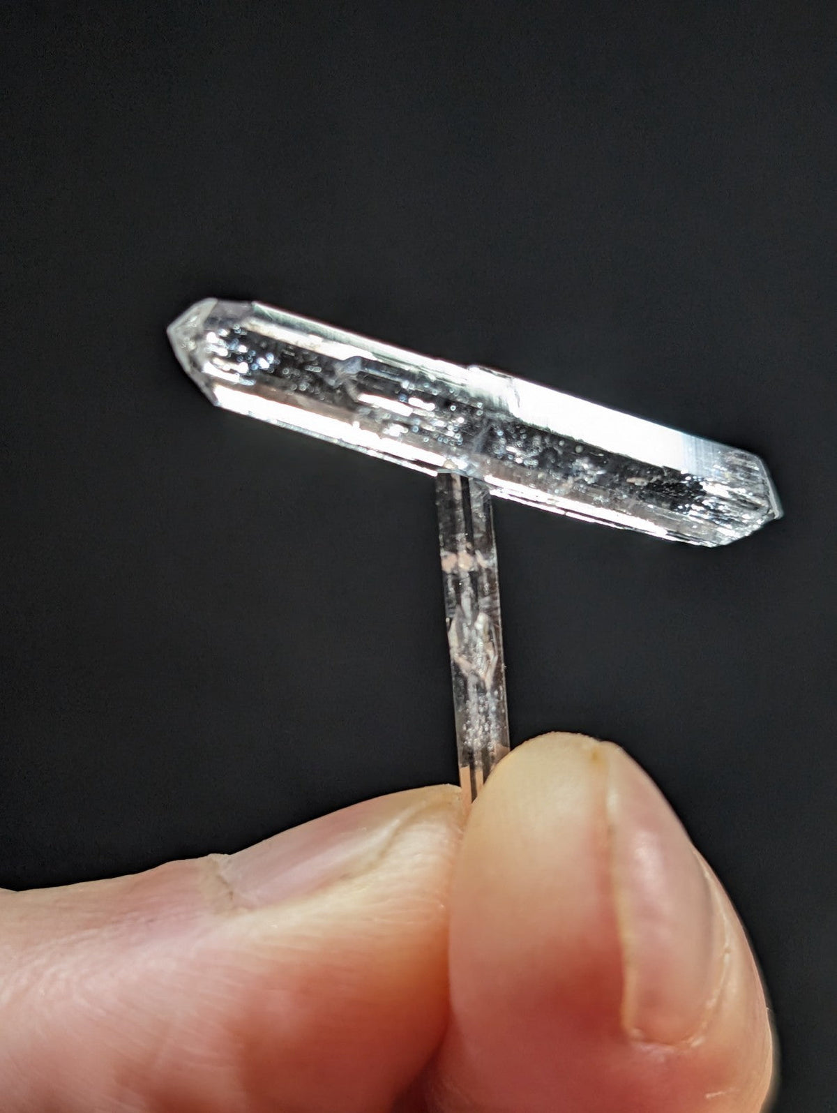 A clear, translucent quartz crystal with a distinct t-shaped structure and visible internal inclusions.