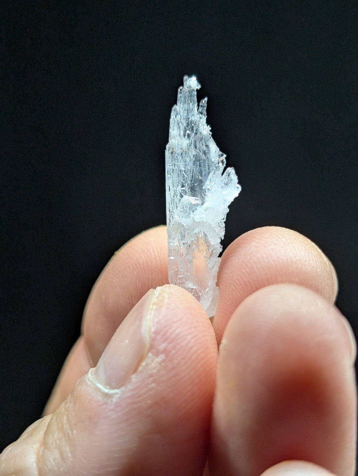A translucent, crystalline mineral specimen with a pointed tip and jagged edges.