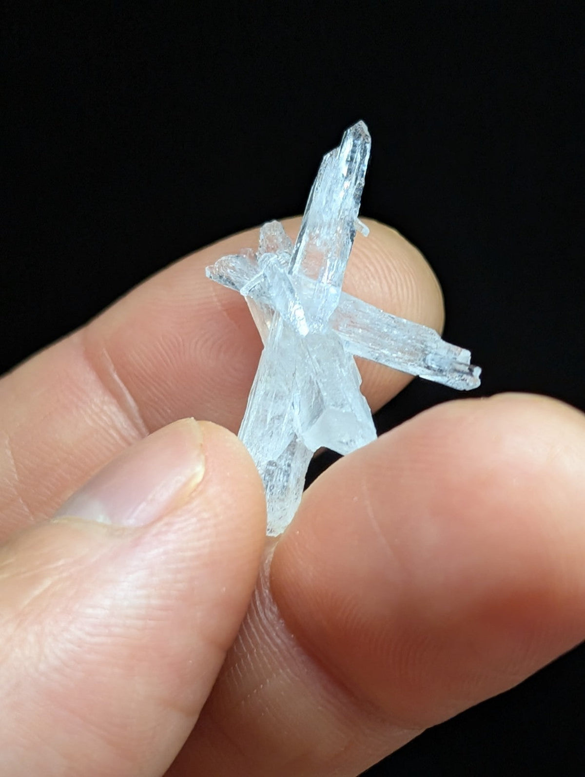 A translucent, light blue crystal formation with sharp, angular facets and a natural cross-like structure.