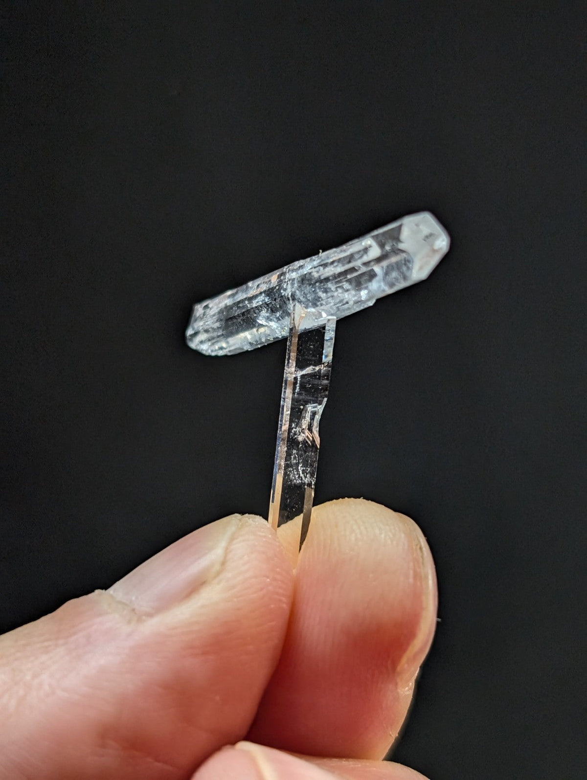 A clear, translucent quartz crystal with a distinct t-shaped form and natural facets.