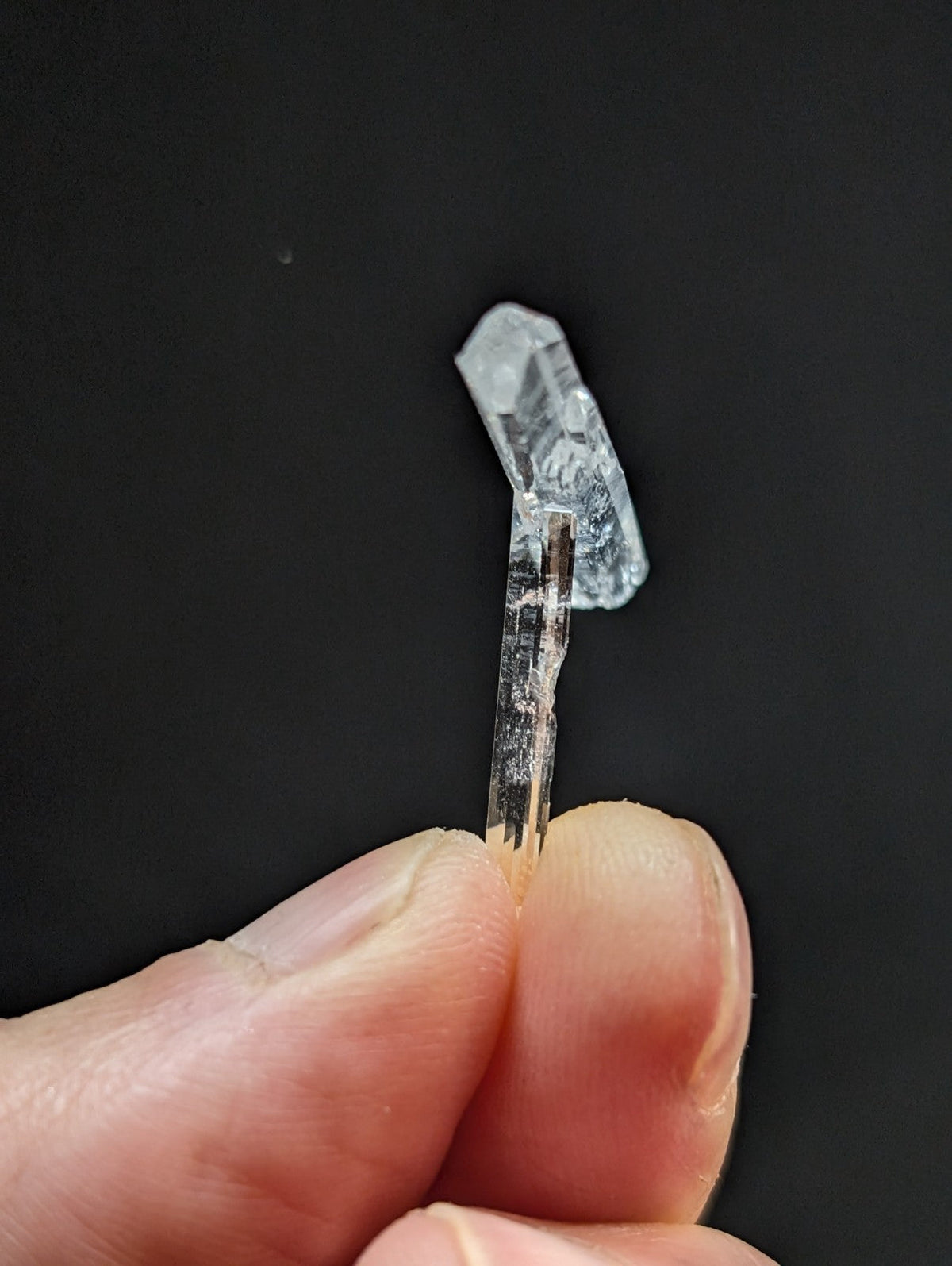 A clear, translucent quartz crystal with a pointed tip and visible internal striations.
