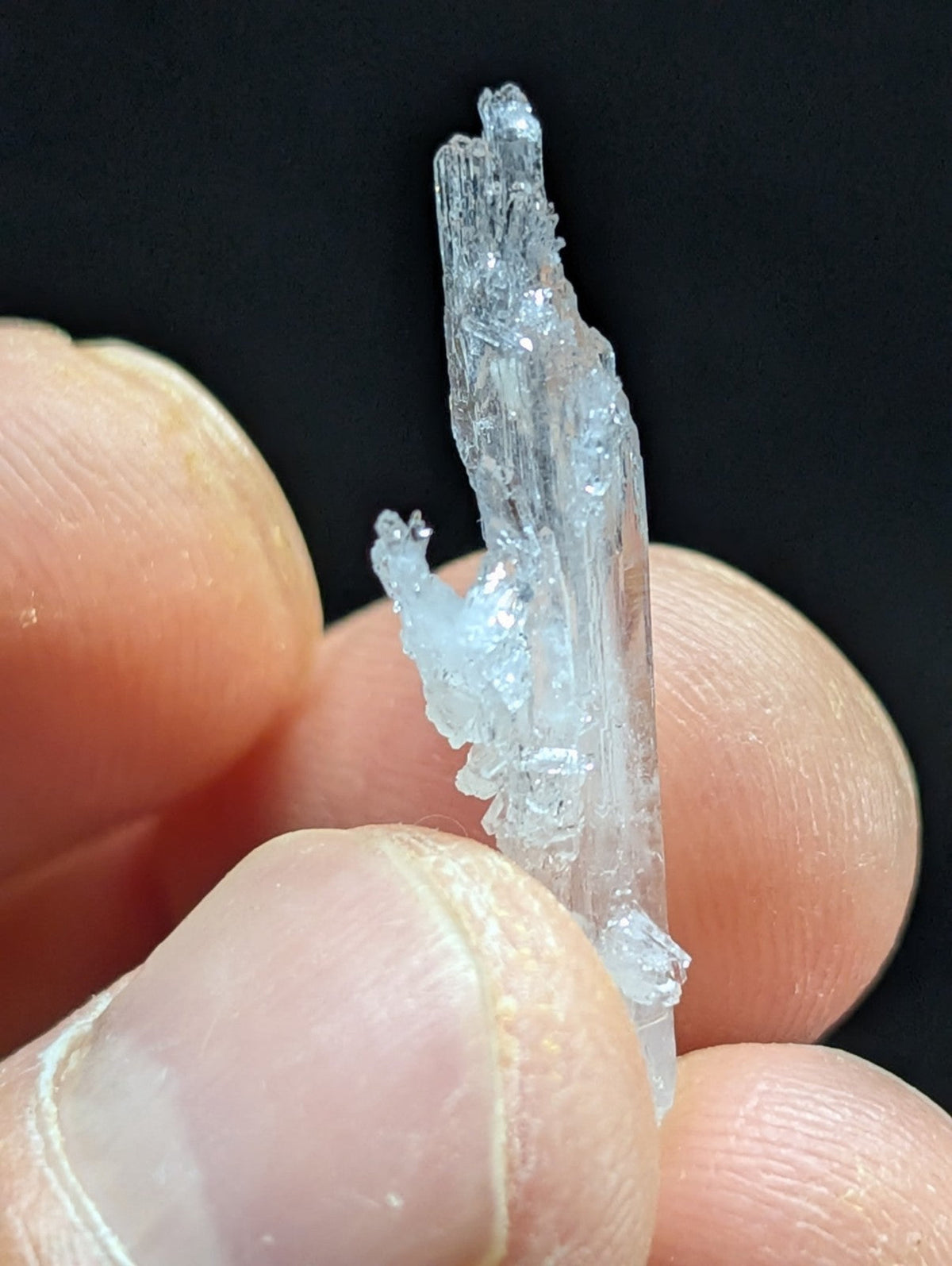 A translucent, crystalline mineral specimen with a jagged, multi-faceted structure and subtle blue tint.