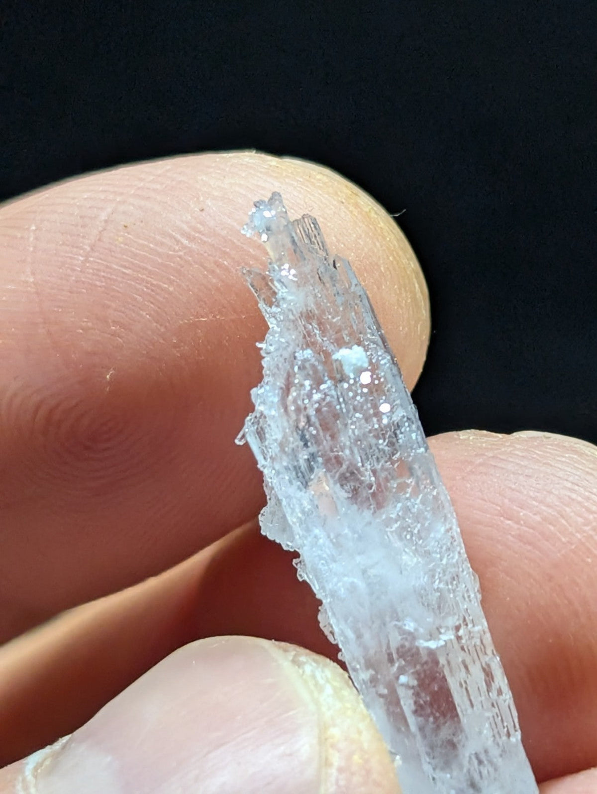 A translucent, crystalline mineral specimen with a jagged, faceted surface and subtle internal striations.