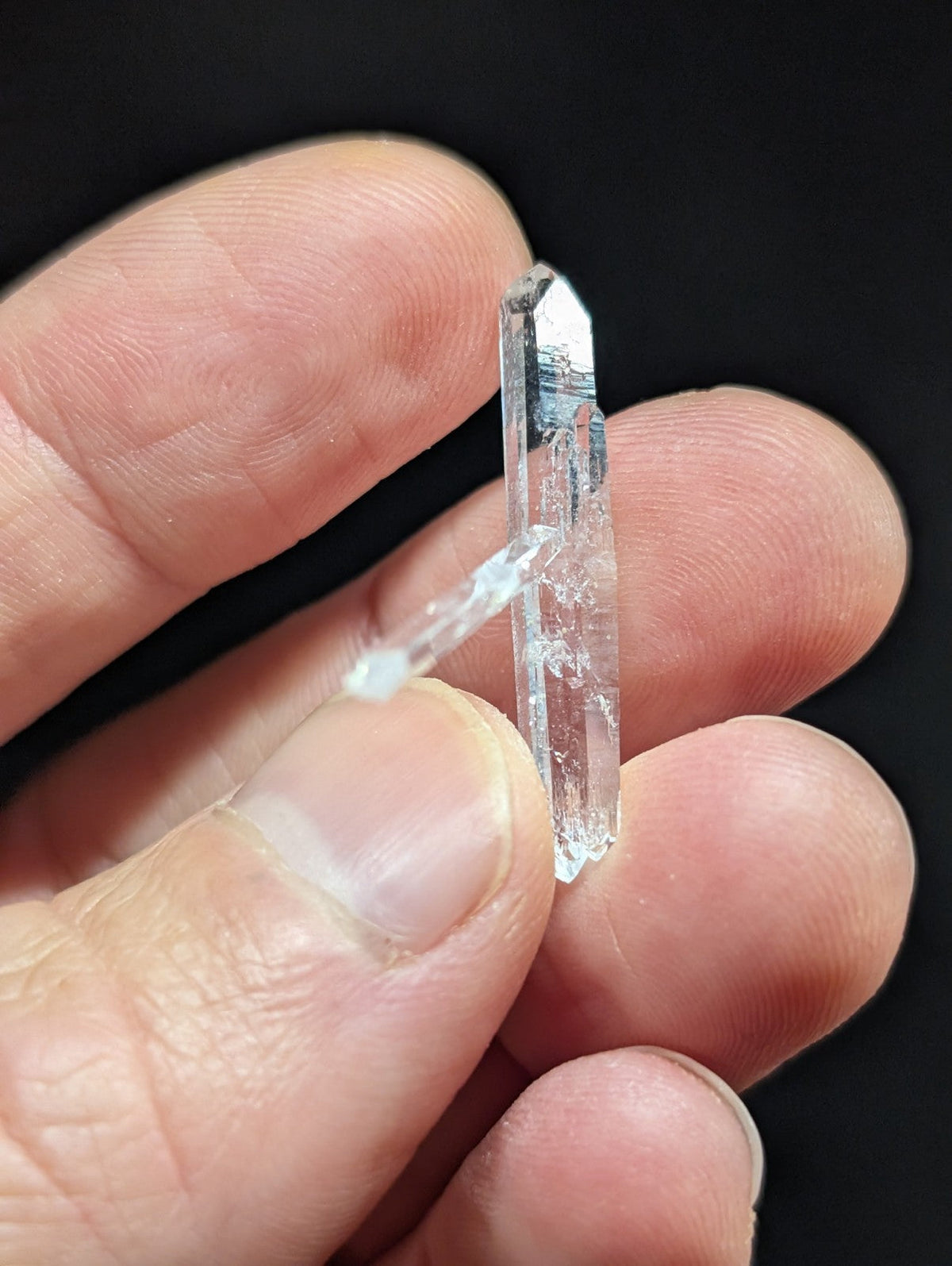 A clear, transparent quartz crystal with a pointed tip and visible internal inclusions.